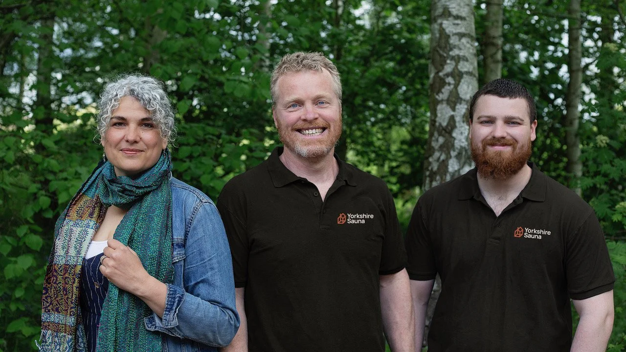 The Yorkshire Sauna team: two co‑founders (business manager and master craftsman) and their son, workshop manager and architectural joiner, standing outside the York workshop.