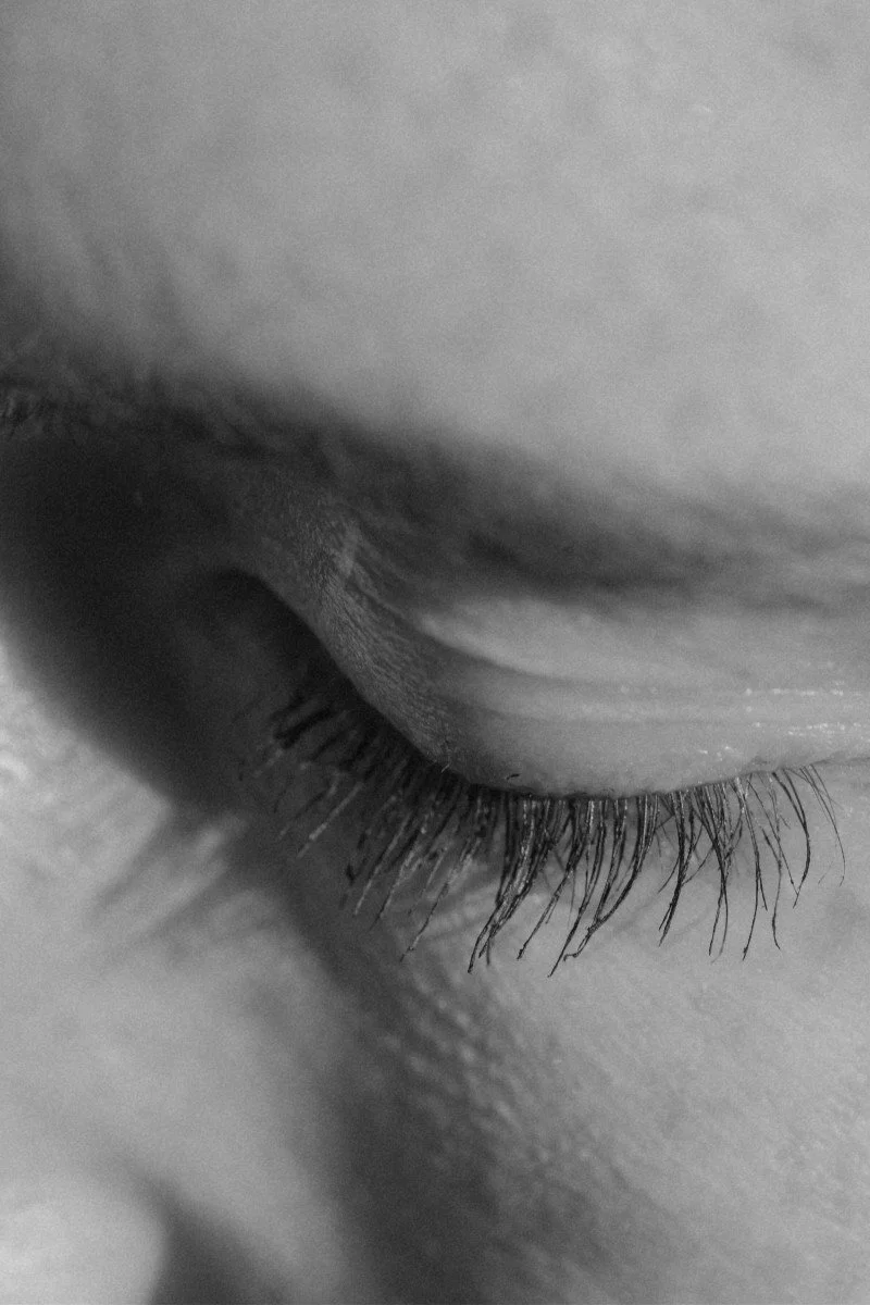 Close-up black and white photo of a closed eye with long eyelashes.