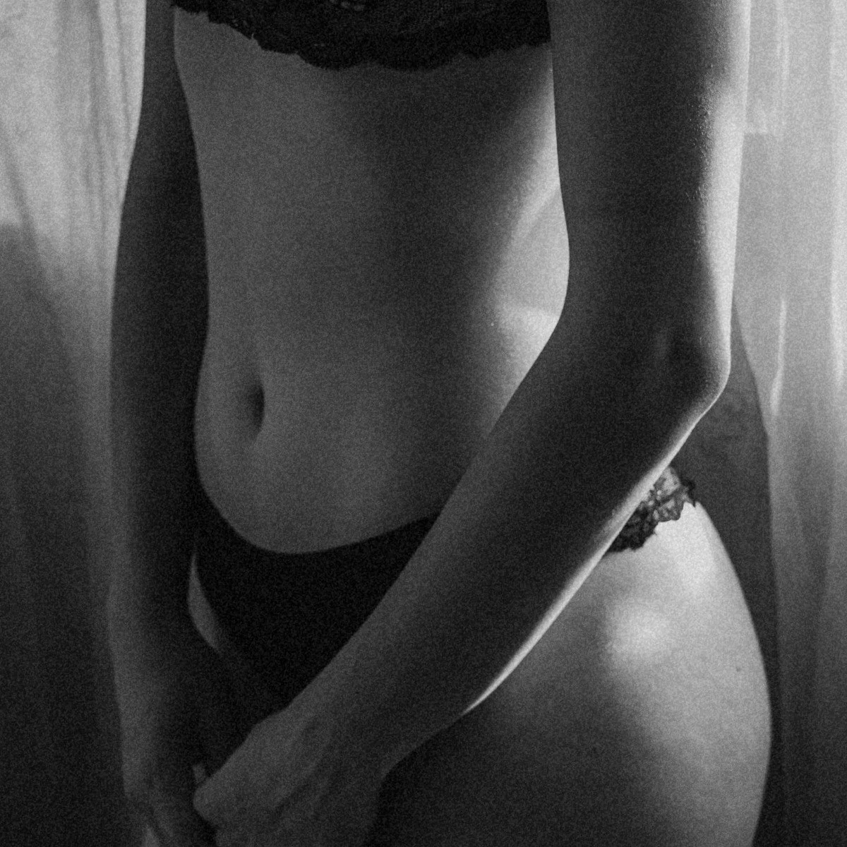 Black and white photo of a woman's torso, waist, and lower body, wearing lace underwear.