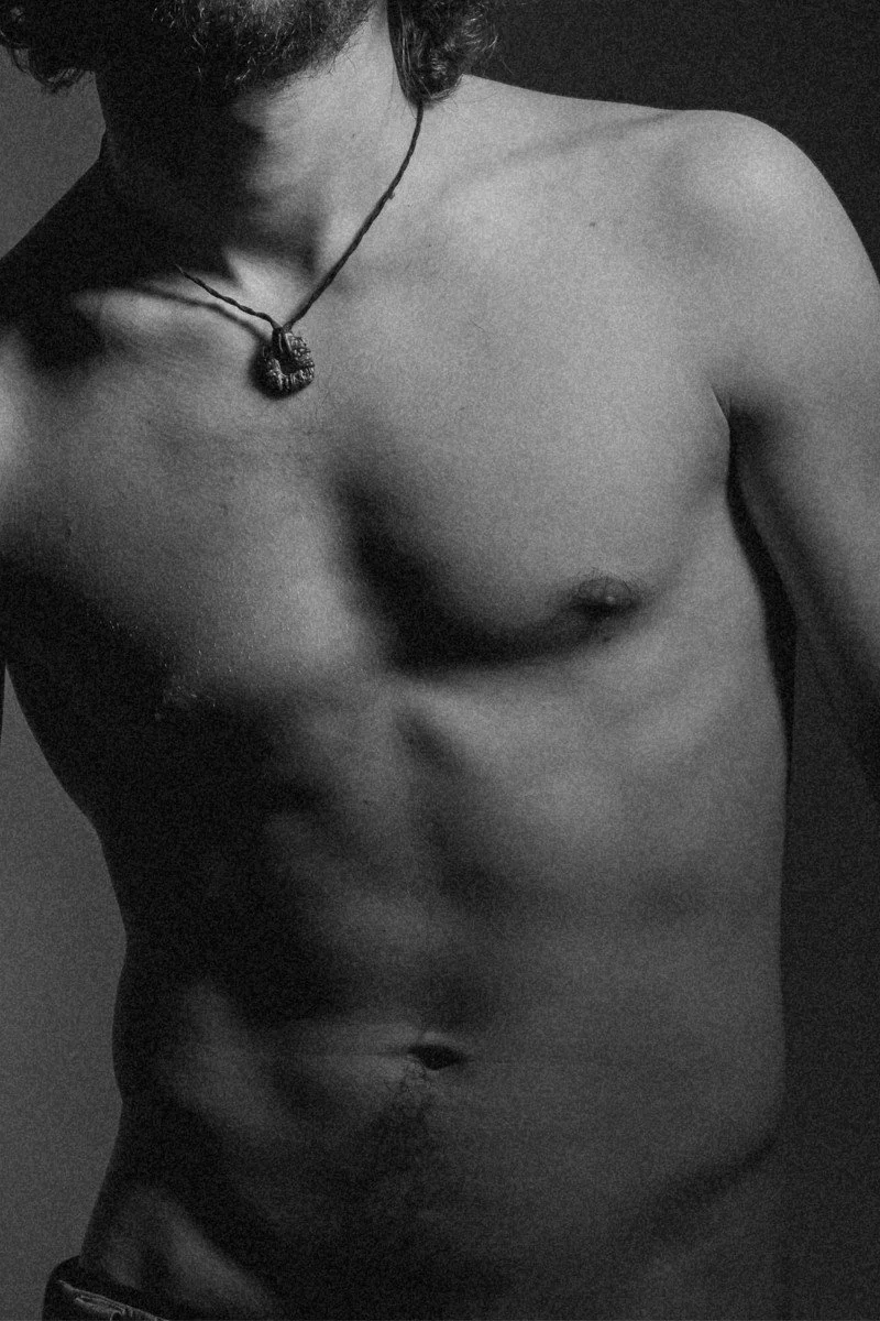 Black and white photo of a shirtless man with a necklace.