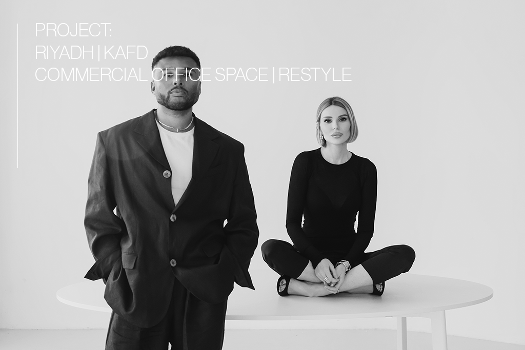 A man in a suit standing beside a woman sitting cross-legged on a table, against a plain white background, with text overlay about a commercial office space project.
