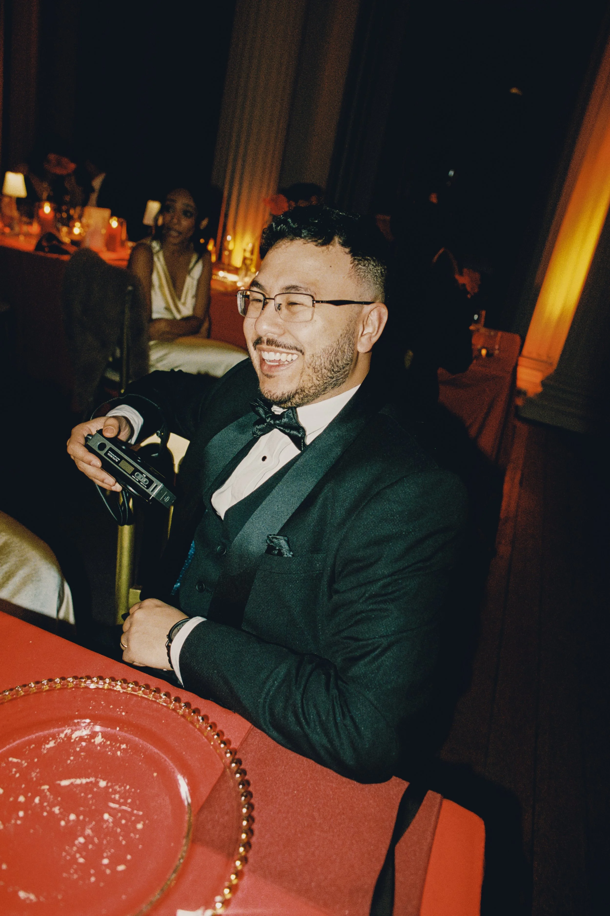 guest candid image smiling with analog camera in hand in Signet Library Edinburgh red tablecloth