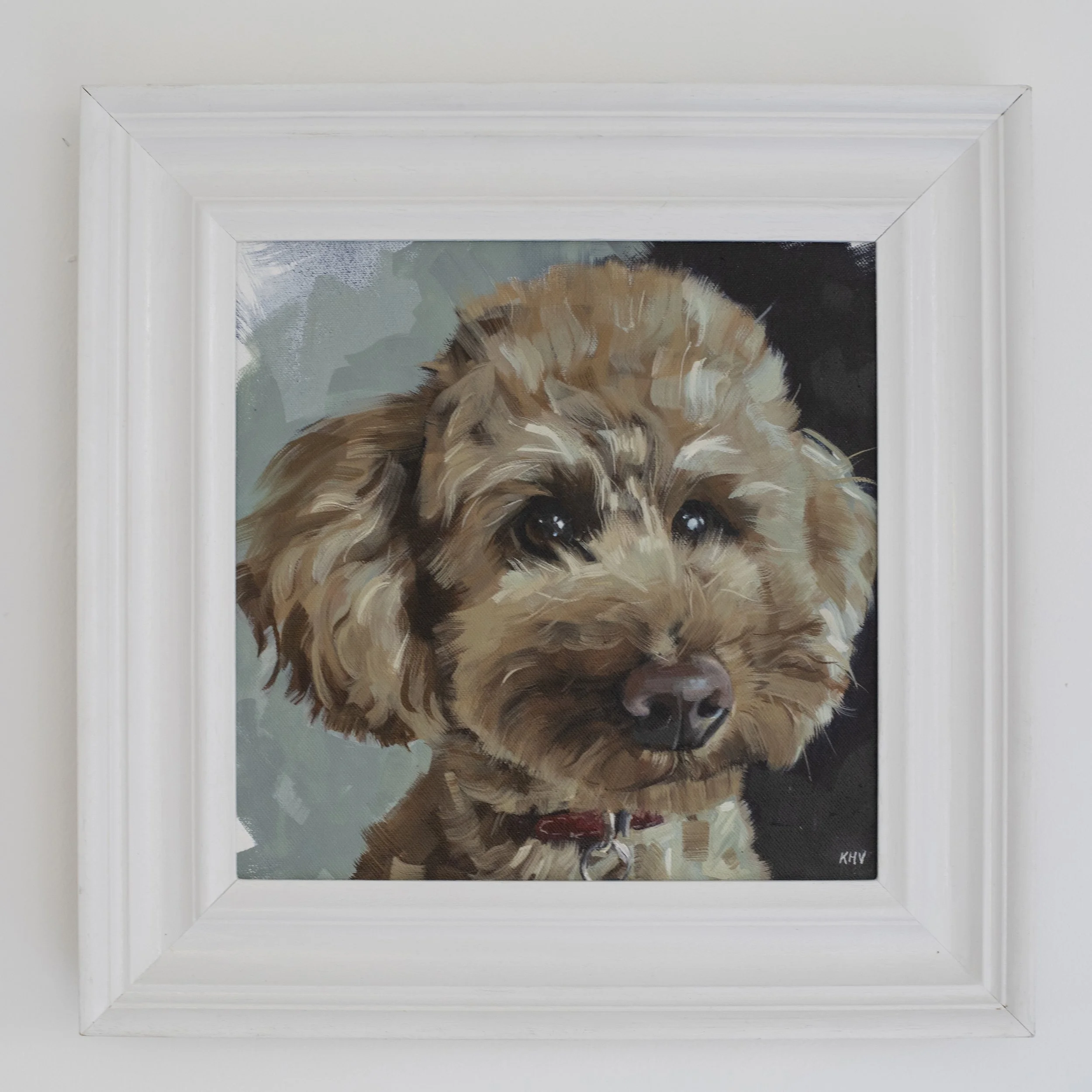 Framed painting of a cavopoo dog with brown fur and large, expressive eyes, signed with initials 'KHV' in the bottom right corner.