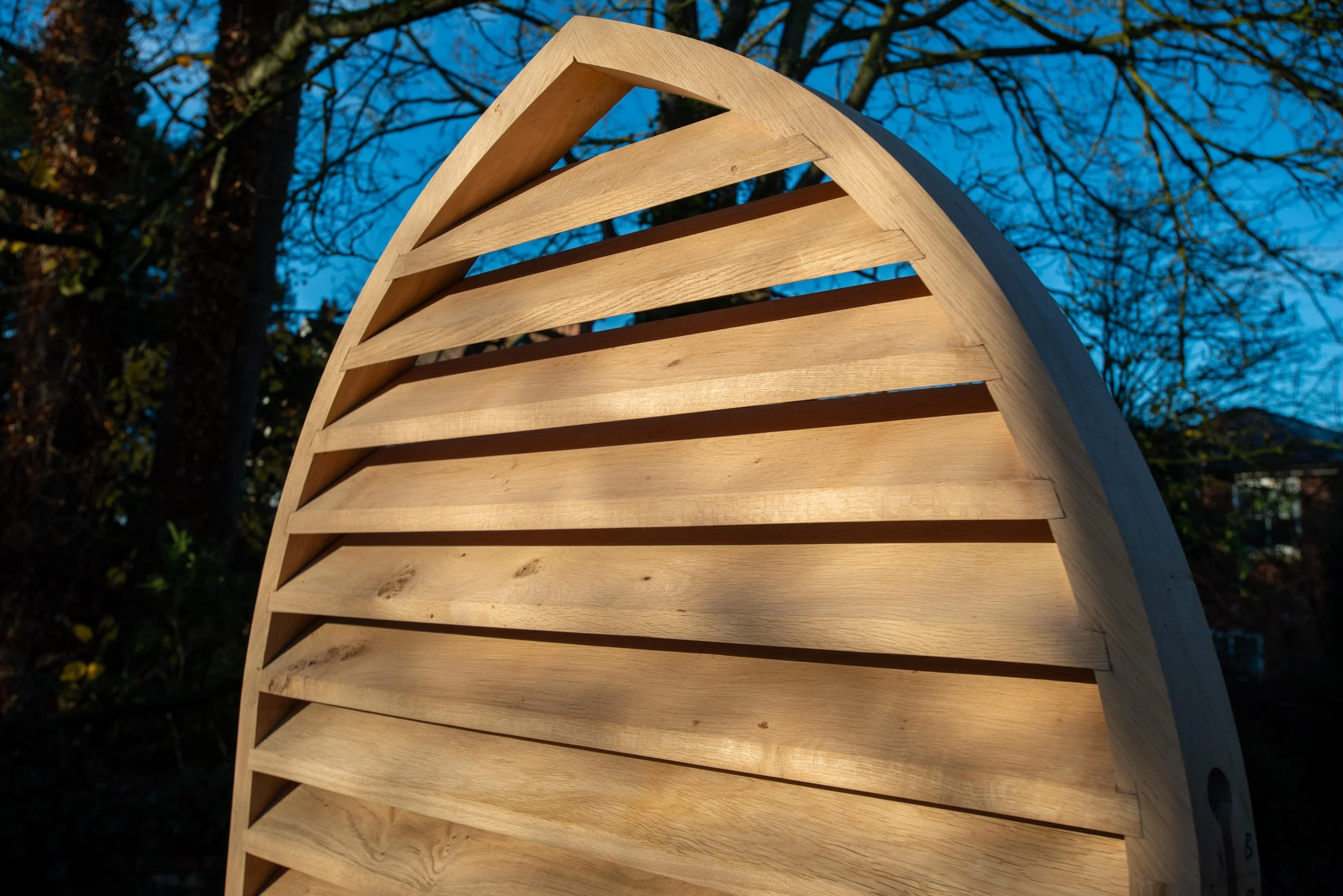 Old brick house with peeling white paint on door and windows, surrounded by bare shrubs, under a clear blue sky.