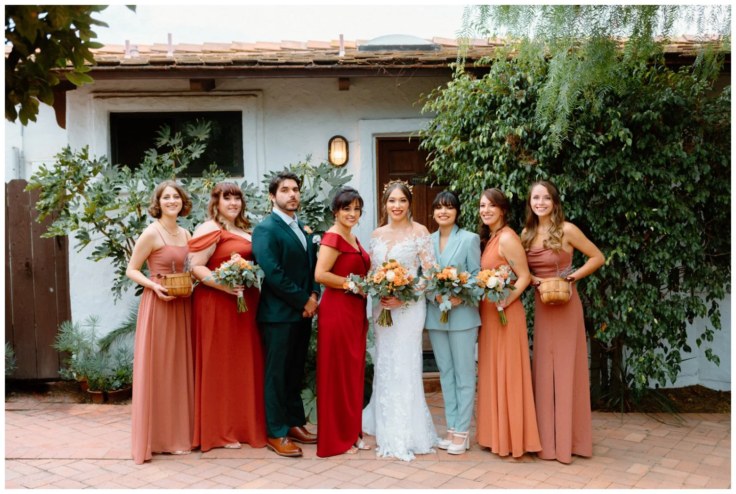 Bride and Bridesmaids formal portrait in rust orange and teal dresses at boho chic wedding Old Rancho Estate, Carlsbad, California
