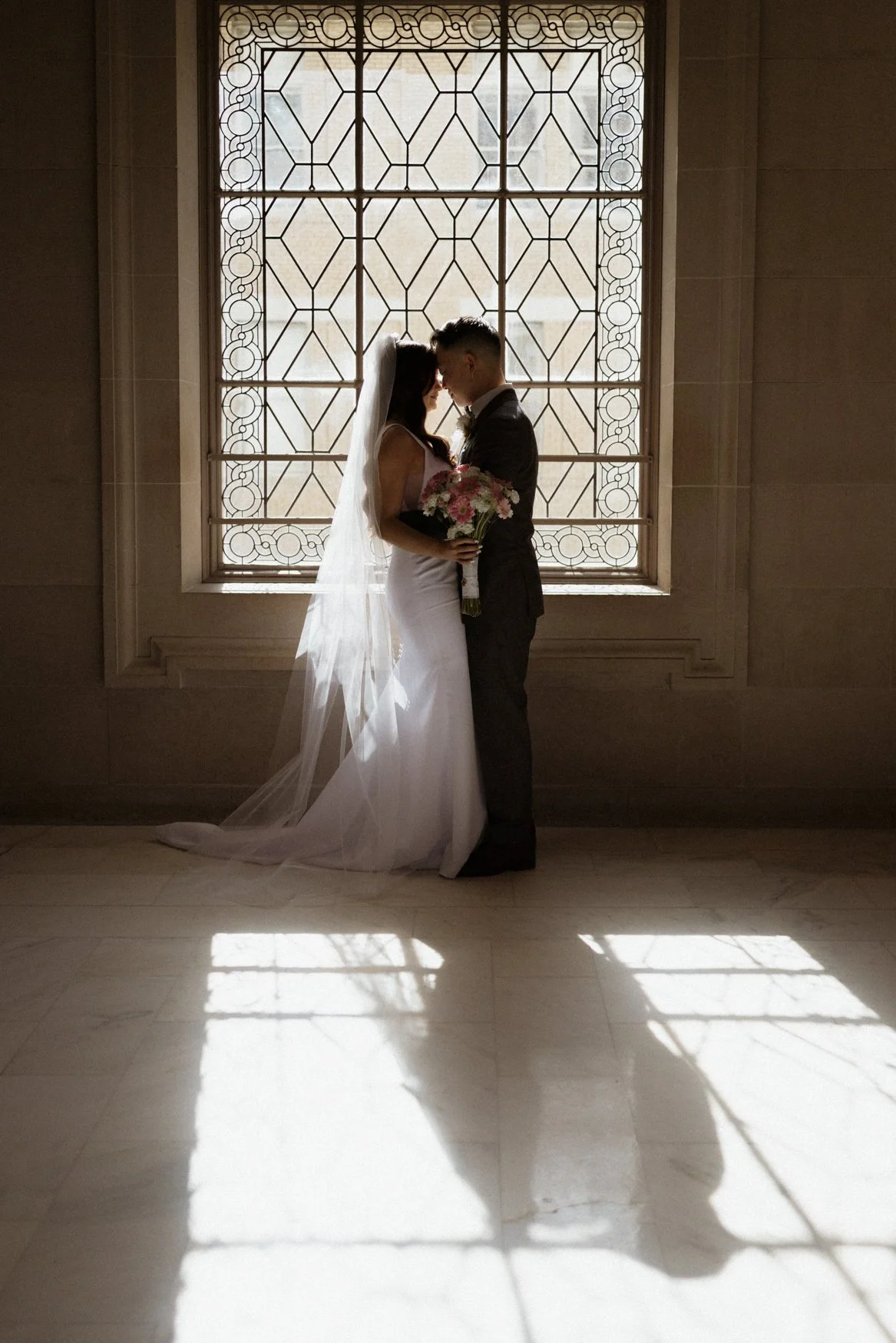 Dramatic silhouette photo of Jonathan and Carla featuring large San Francisco City Hall Windows