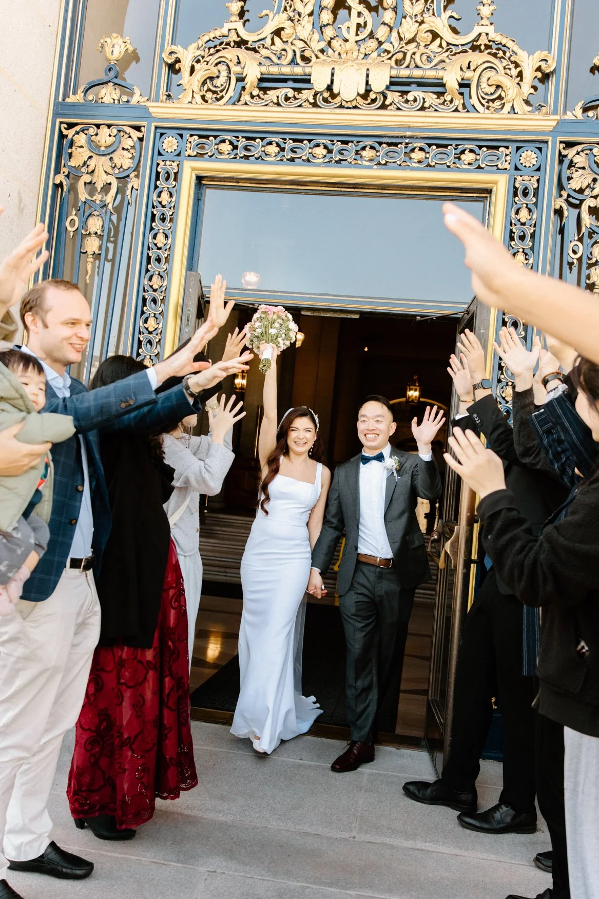 Jonathan and Carla's grand exit with SF City Hall's blue and gold doors by By Evening Photography, San Francisco Bay Area wedding photographer