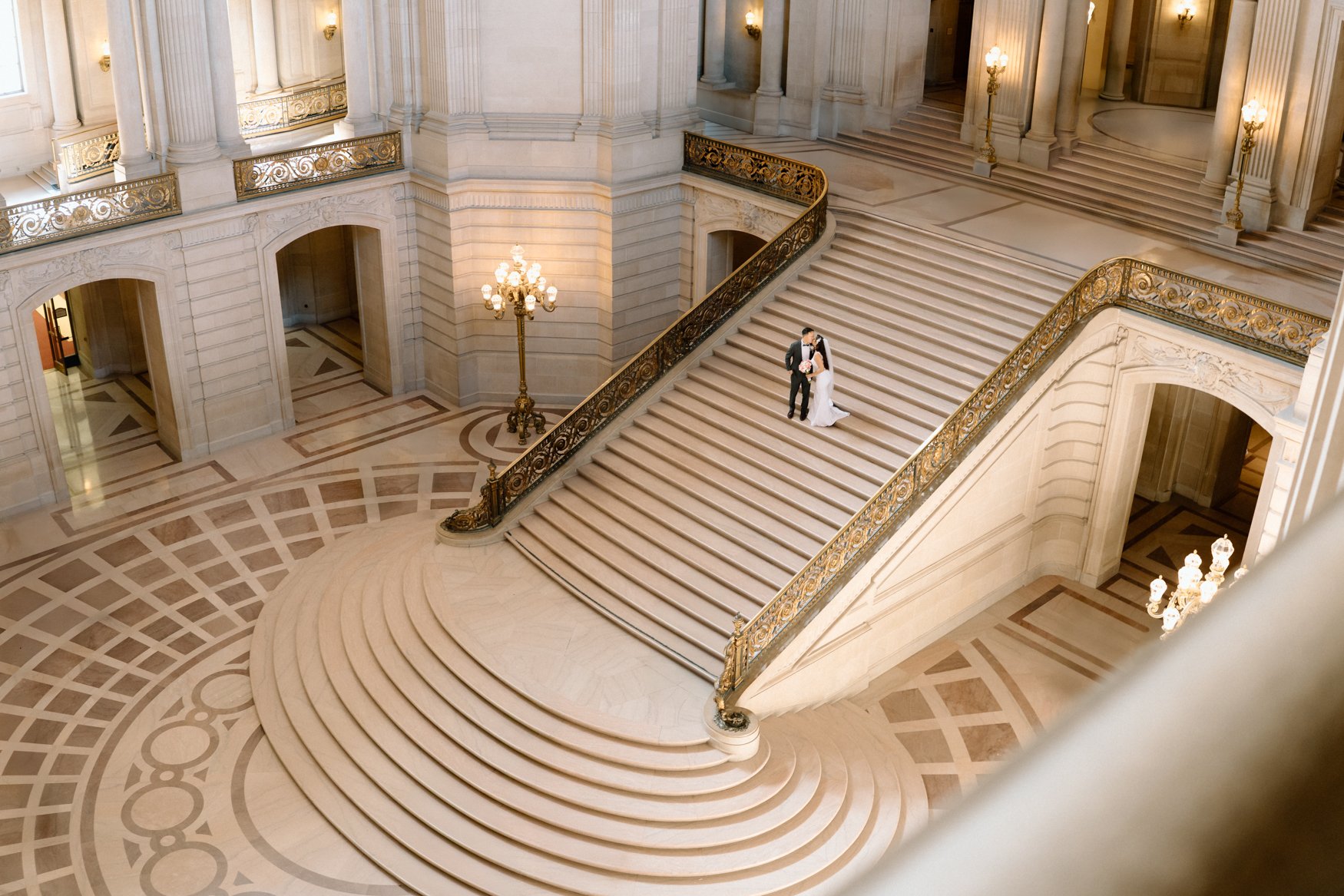 Couple standing beneath the ornate architecture of San Francisco City Hall during their wedding