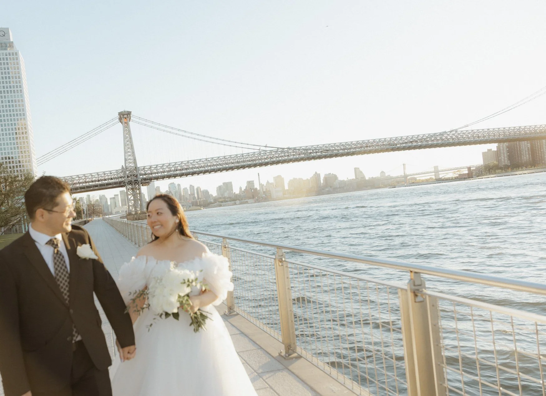 Soft focus of Theresa and Lucky walking with Brooklyn, Bronx, Manhattan skyline in the background.