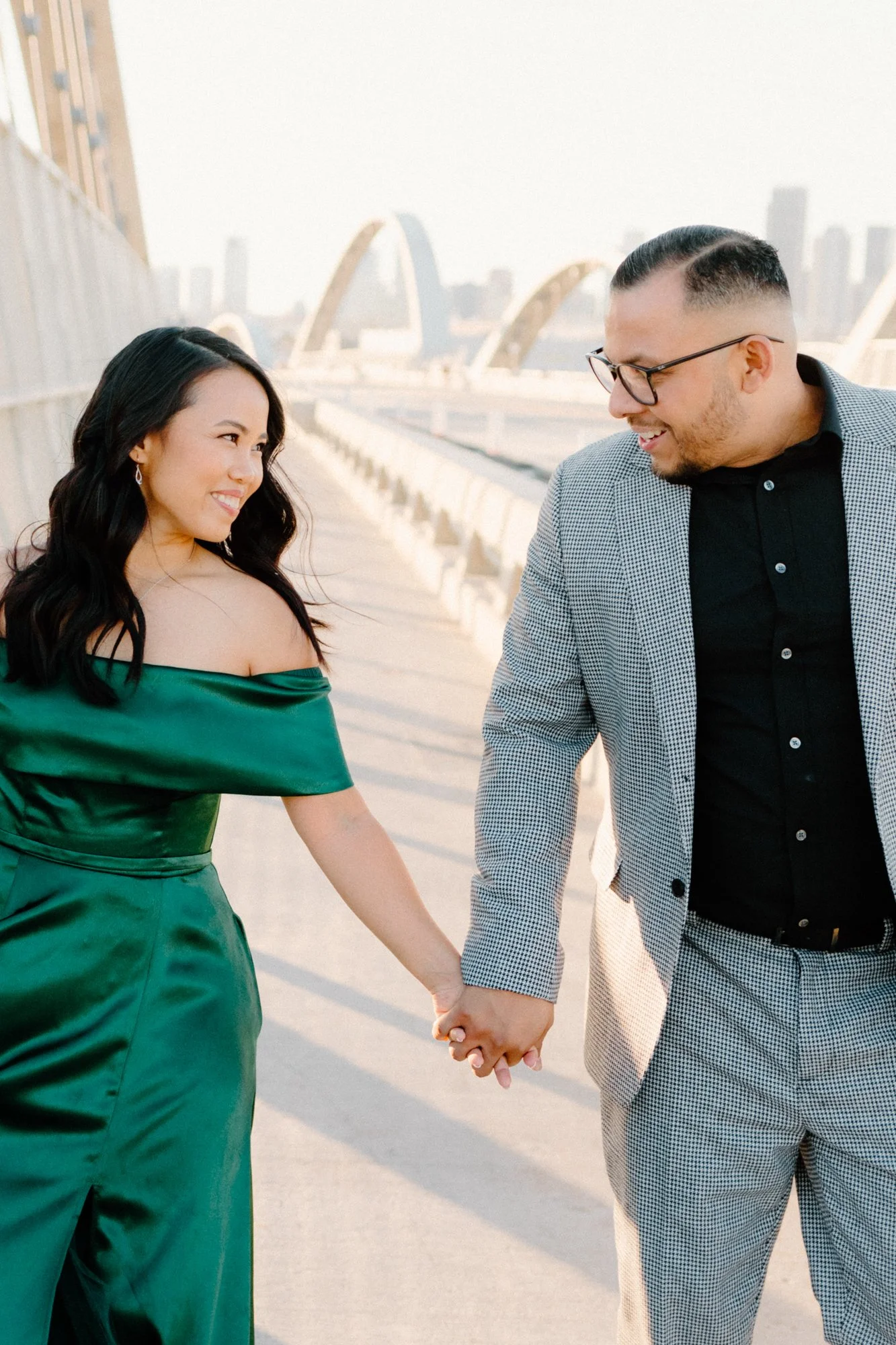 candid cinematic engagement photo of a couple on 6th street bridge holding hands and smiling at each other