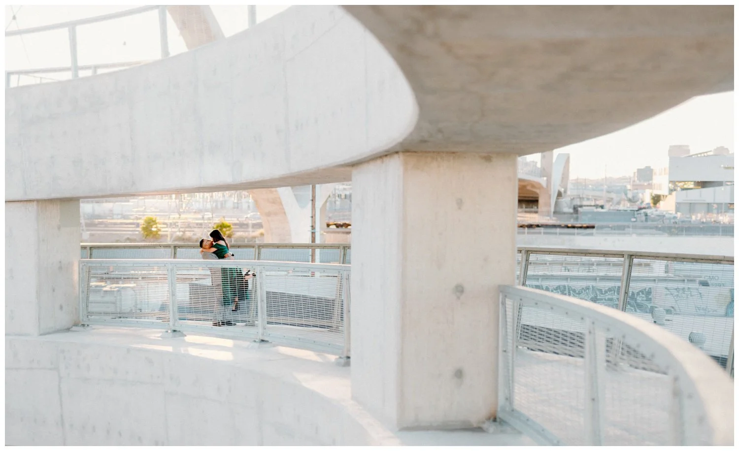cinematic photo at sunset of an engaged couple kissing in an iconic los angeles spot, 6th street bridge.