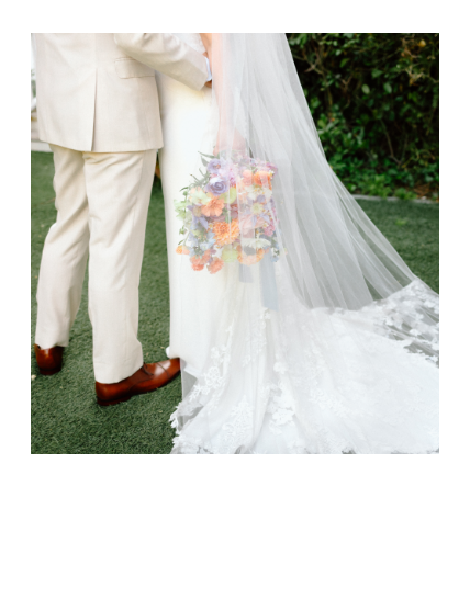 editorial wedding photography detail photo of groom in cream suite holding bride with spring colored bouquet with veil over top
