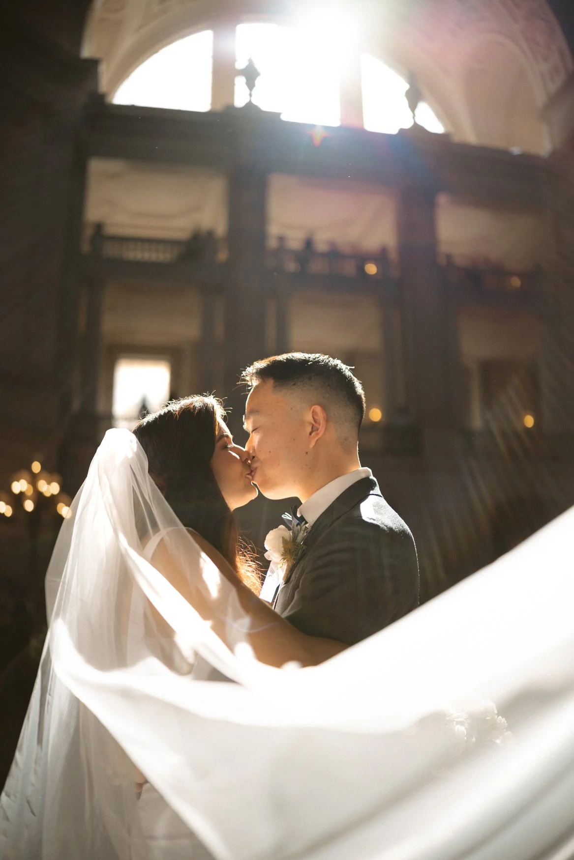 Editorial Veil photo of bride and groom in the San Francisco City Hall lobby, bathed in sunlight