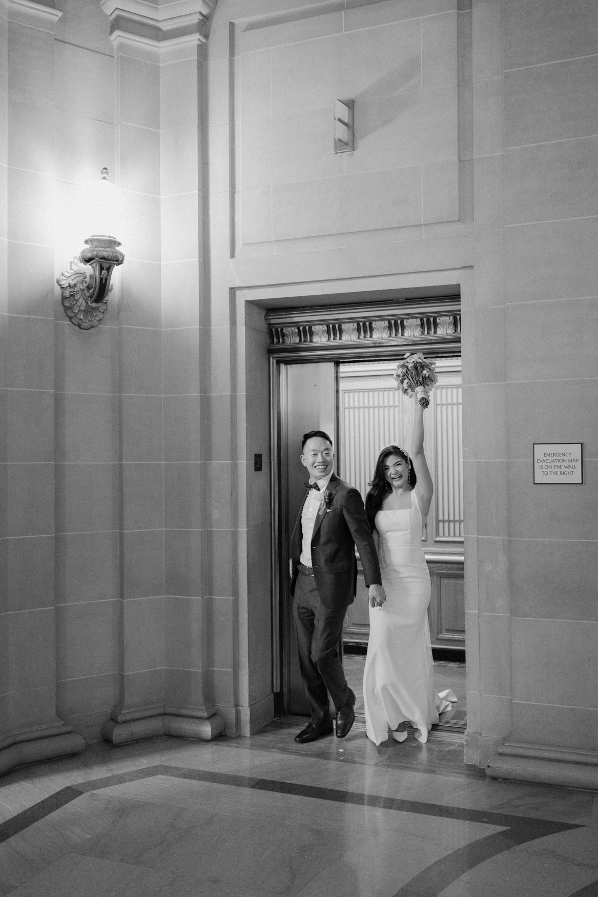 Documentary wedding moment of Jonathan and Carla exiting the elevator at San Francisco City Hall