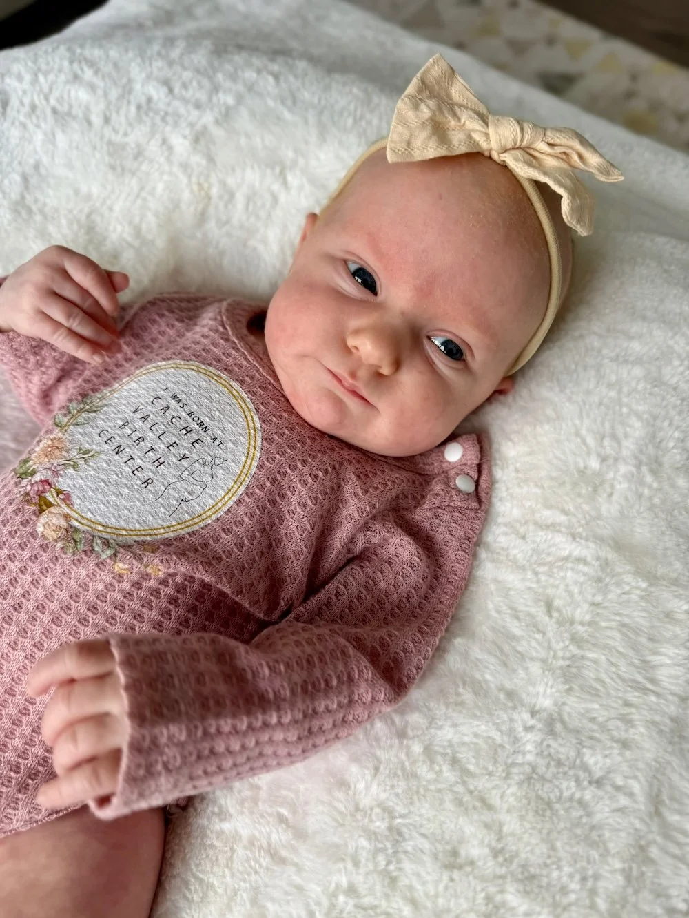 Newborn baby girl wearing a Cache Valley Birth Center onesie after a successful natural delivery in Logan, Utah