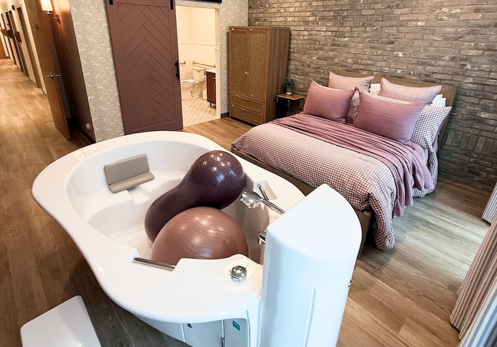 Spacious birth suite with a deep water birth tub, birthing balls, and comfortable bed at Cache Valley Birth Center