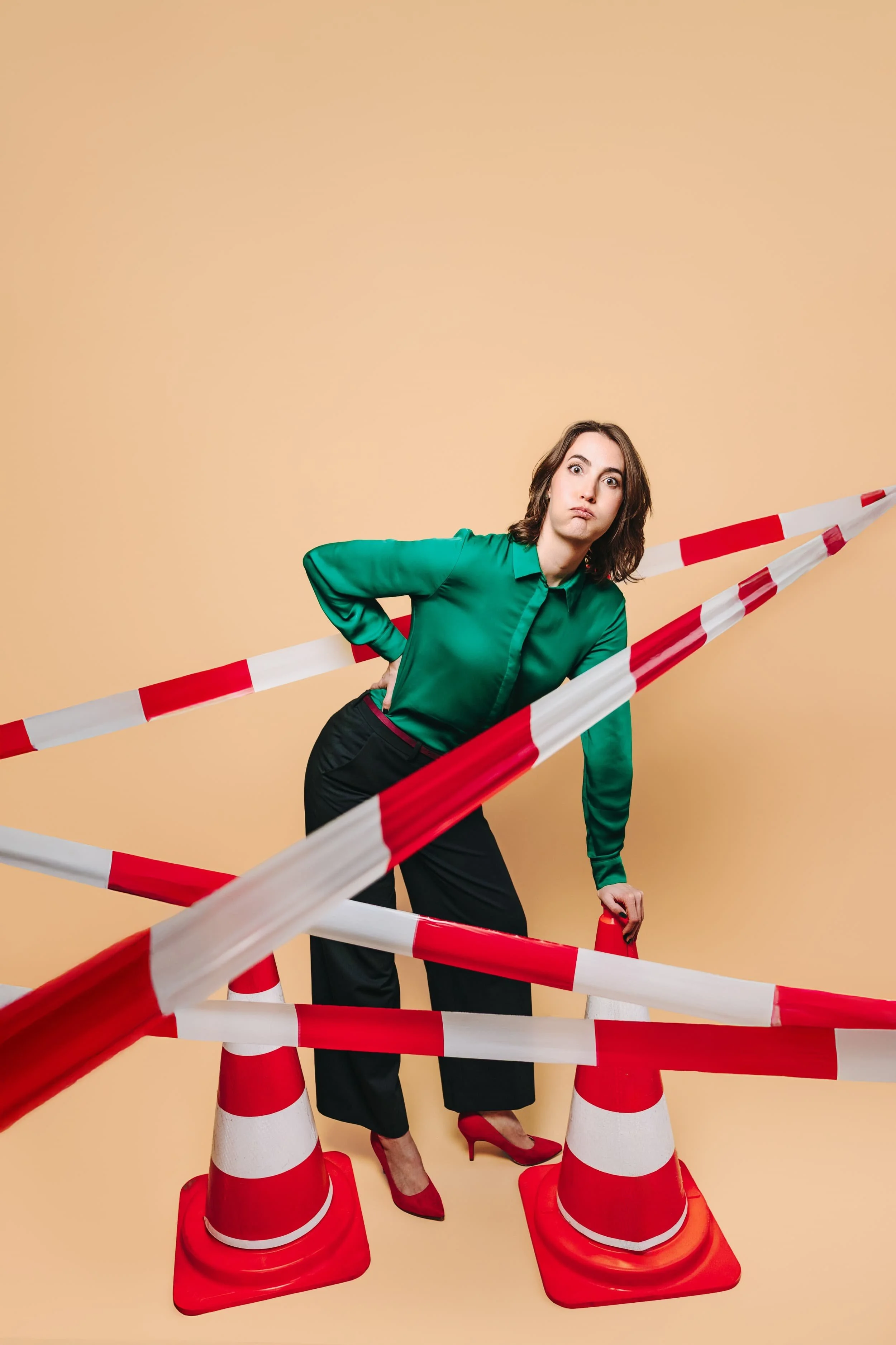 Portretfoto van freelance SaaS-copywriter en contentstrateeg Marije van Wijngaarden, gekleed in een groene blouse met zwarte panterprint, fronsend en werkend aan een oranje vintage computermonitor met oranje toetsenbord en muis.