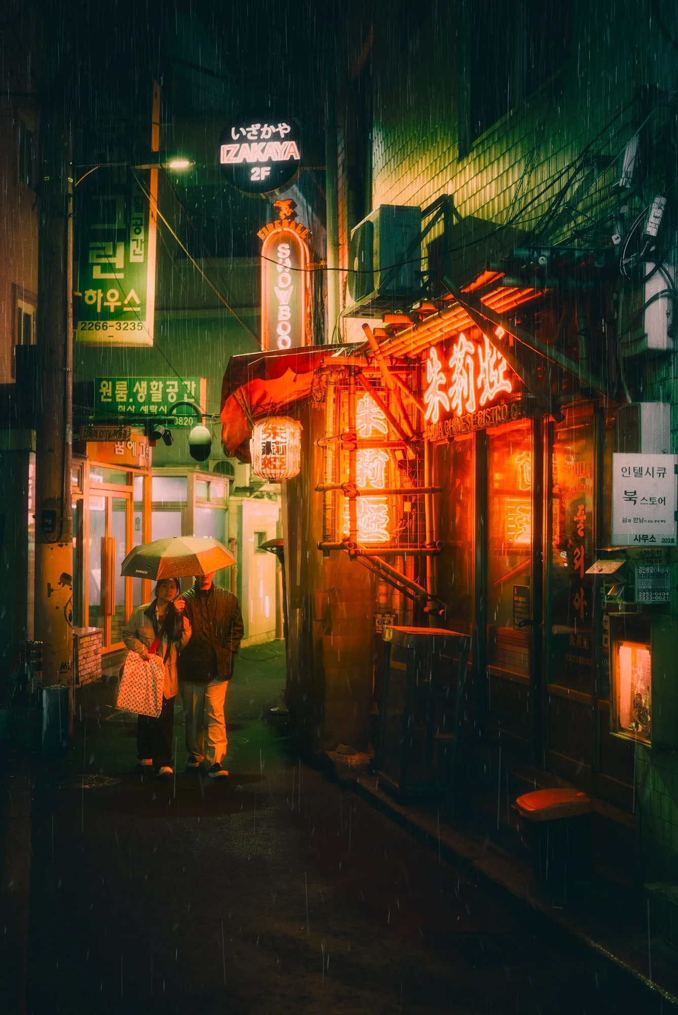 Rainy night scene of two people with an umbrella walking in a narrow alley illuminated by neon signs and lanterns, with wet pavement reflecting the lights.
