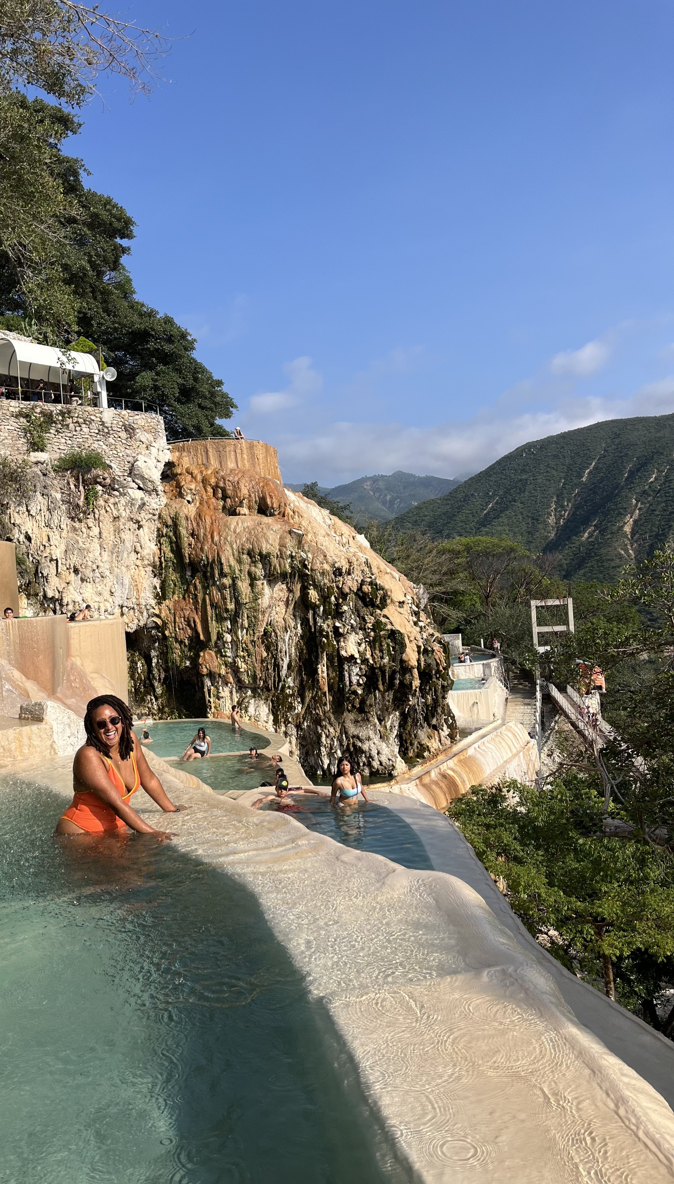 People enjoying a hot spring with waterfalls and mountain view in Bali, Indonesia