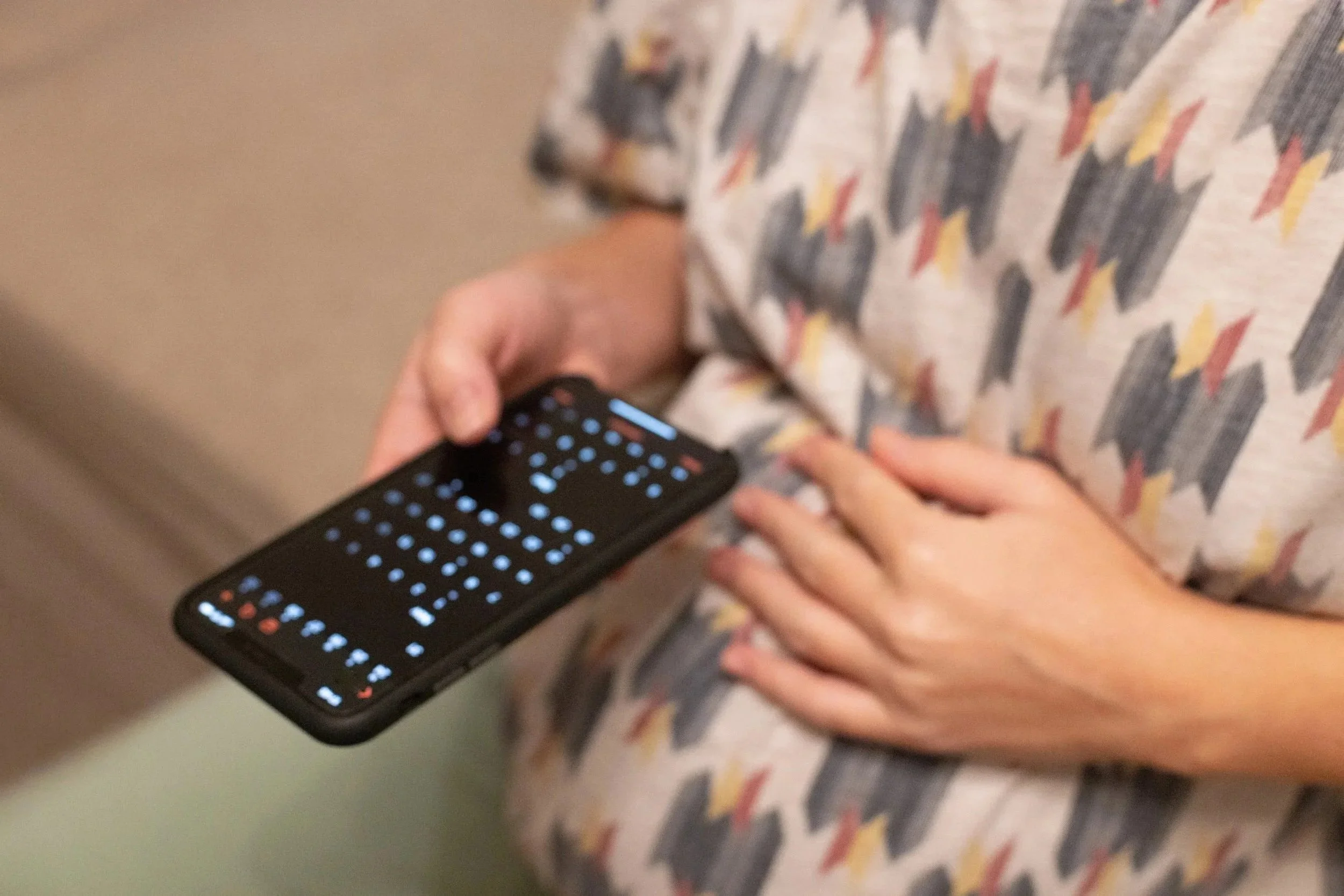 A pregnant woman looks at a calendar using her mobile phone.