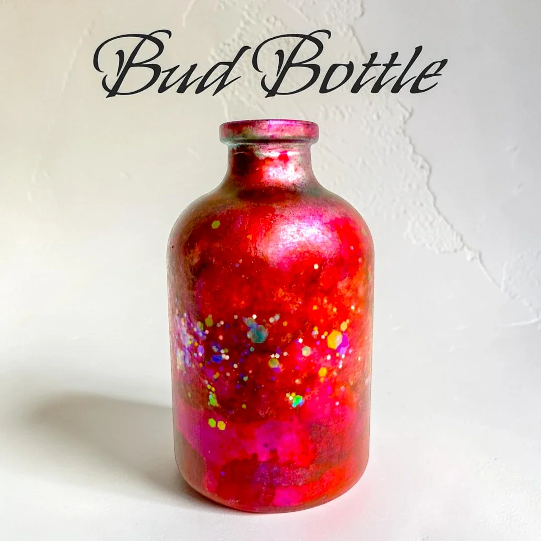 An amber glass apothecary bottle which has been hand-painted in vibrant uv-reactive colors.