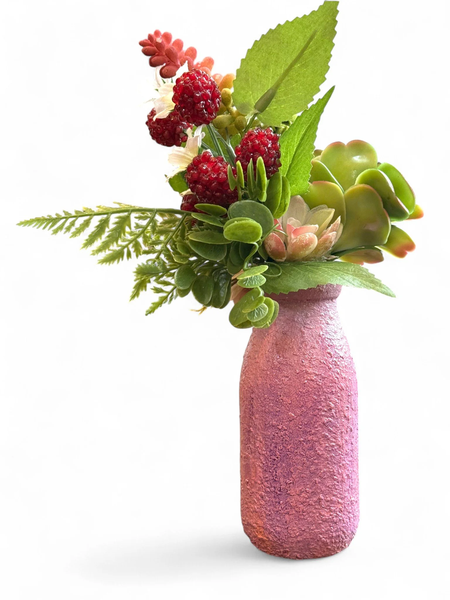 Colorful artificial floral arrangement with blue and yellow flowers in a decorated pink and purple textured vase against a light blue background.