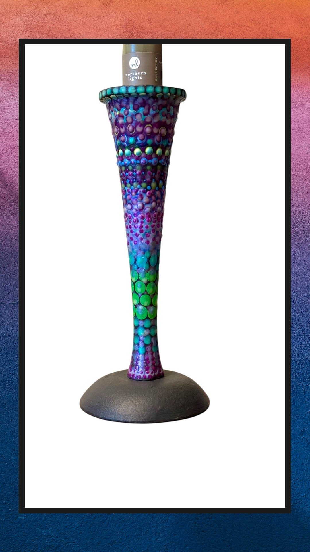 Colorful, textured vase with a pattern of raised dots, containing a brown bottle with a label that reads 'northern lights'