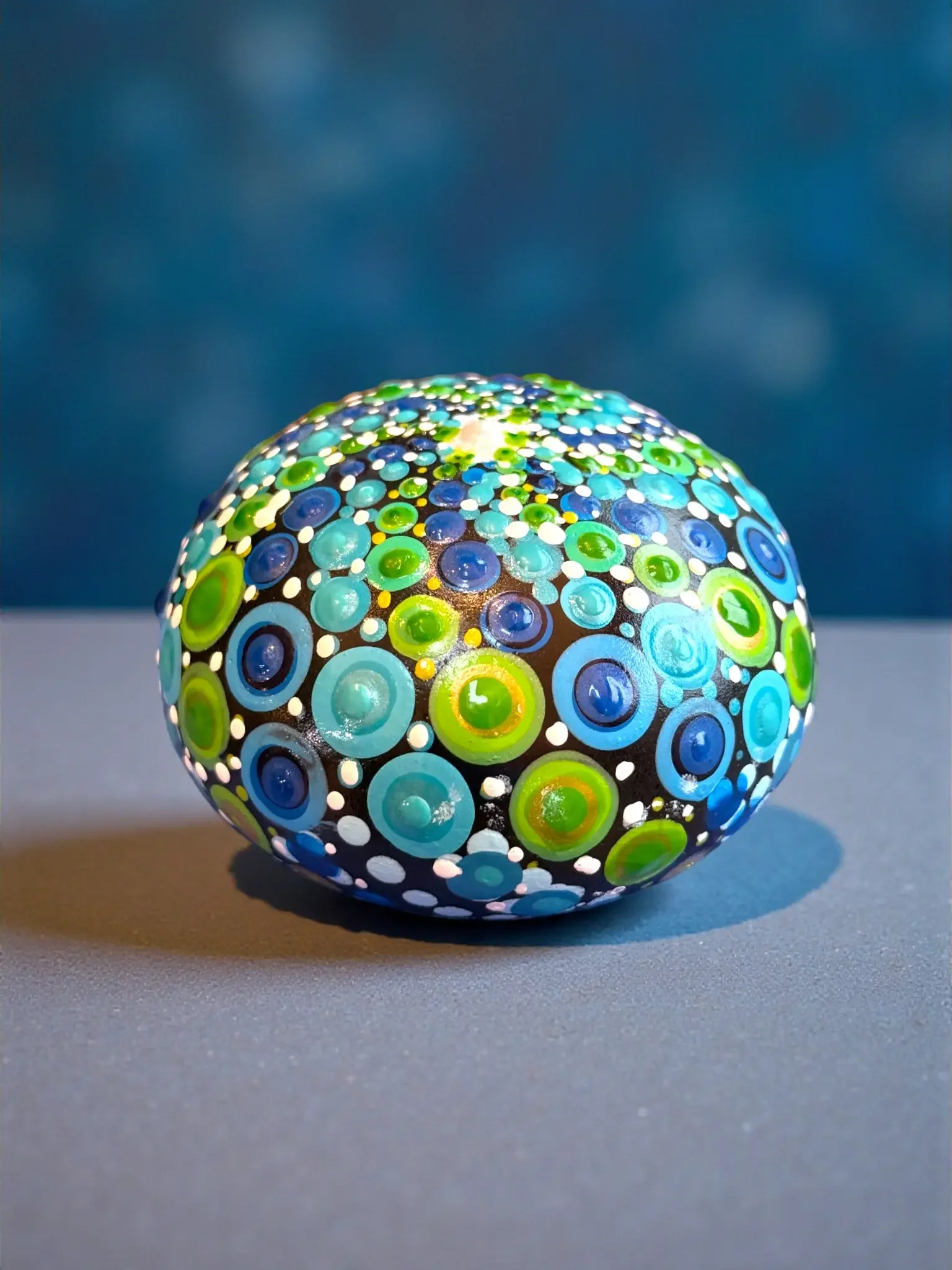 Dumpling Mandala Stone by Color Cult featuring blues and green dot mandala artwork.
