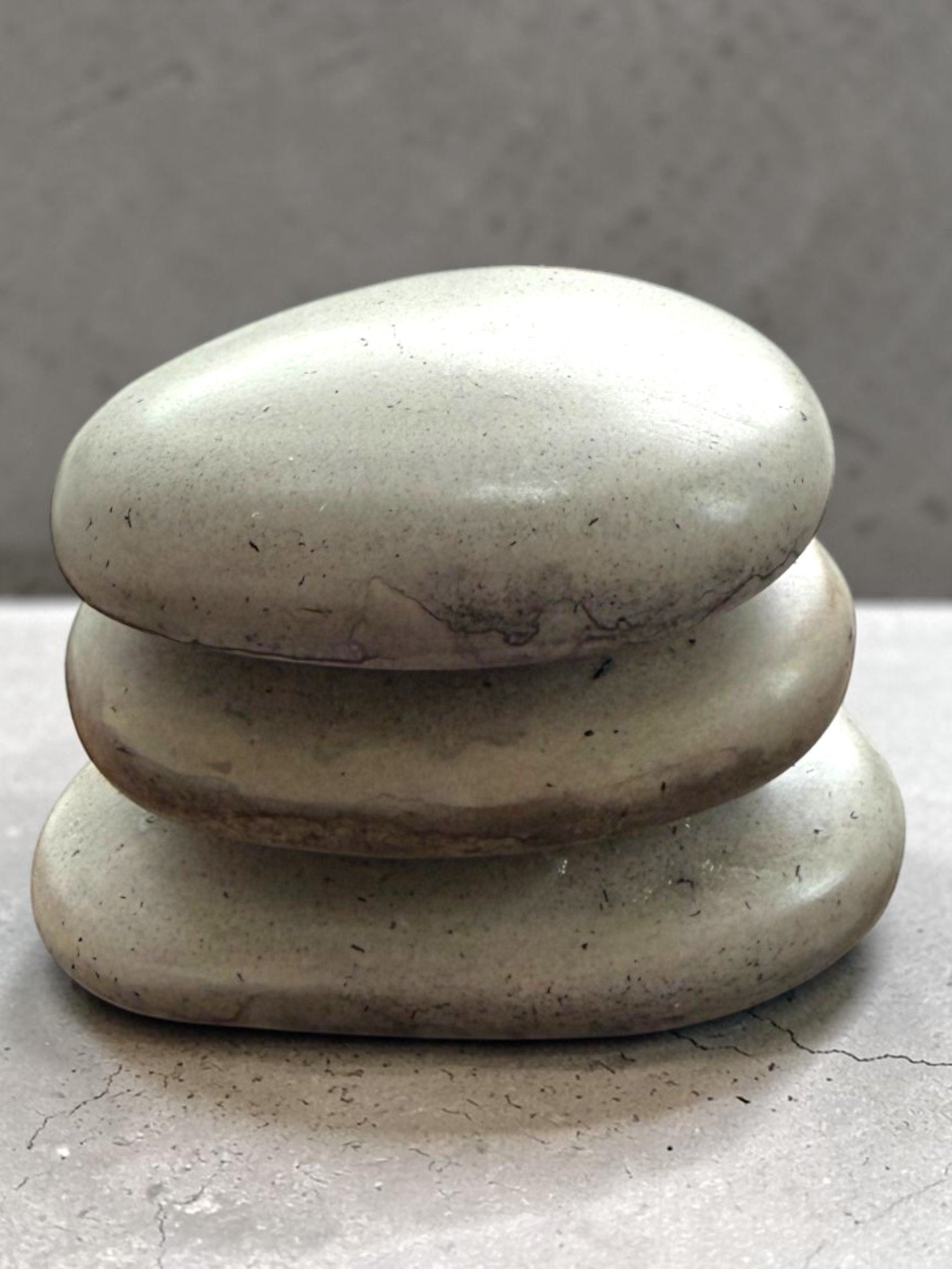 Stacked smooth, white stones on a concrete surface with a plain background.