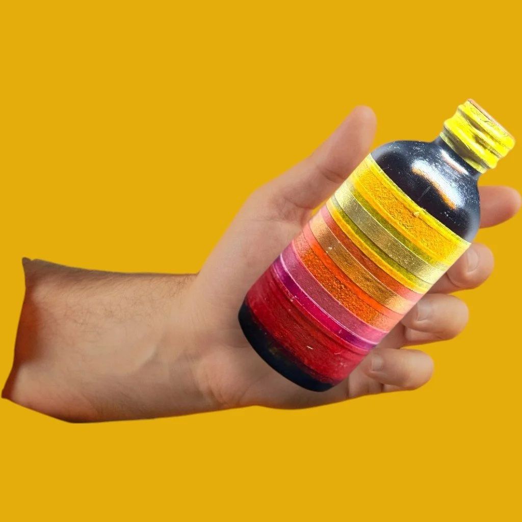 A hand holding a small bottle painted with horizontal stripes in yellow, gold, orange, pink, and red, against a solid yellow background.
