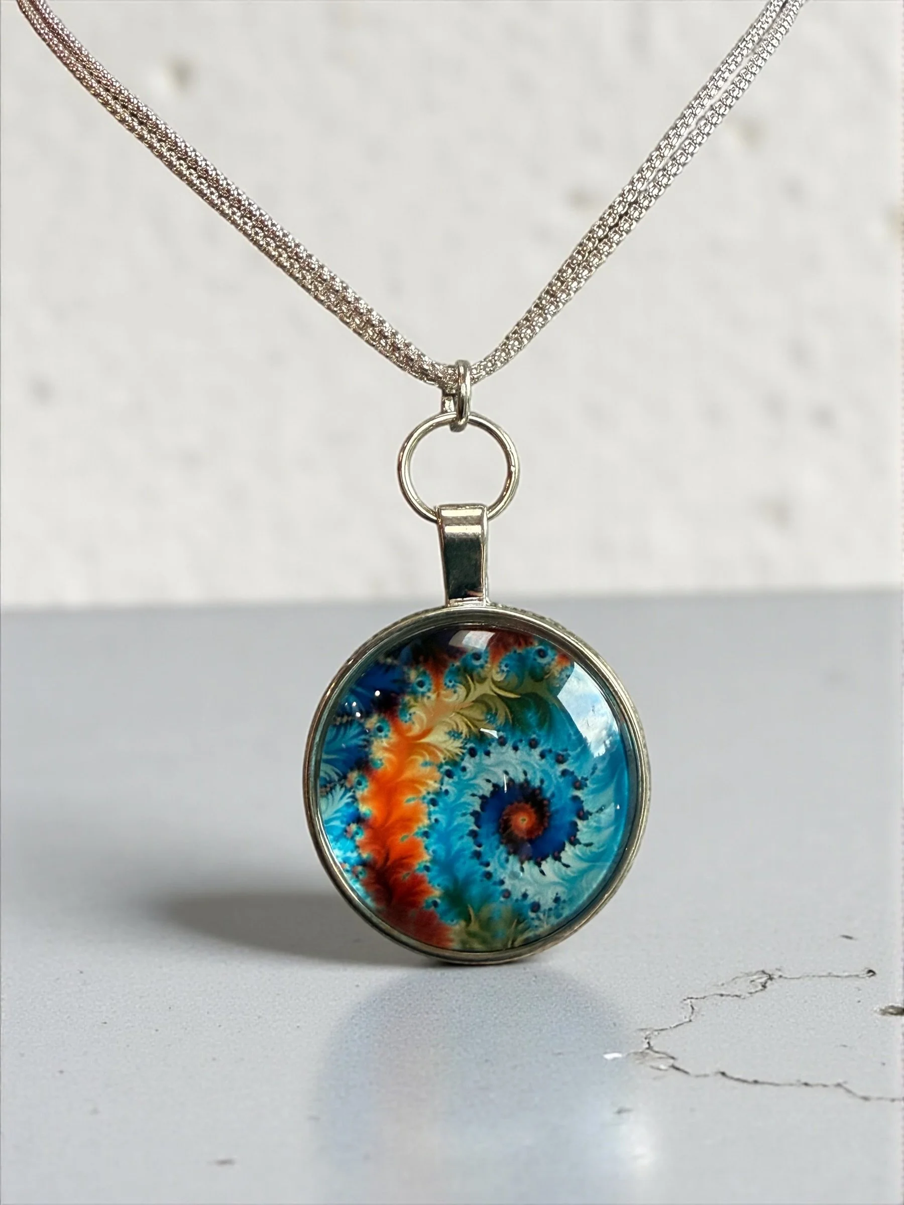 Gold chain necklace with turquoise pendant on black background.