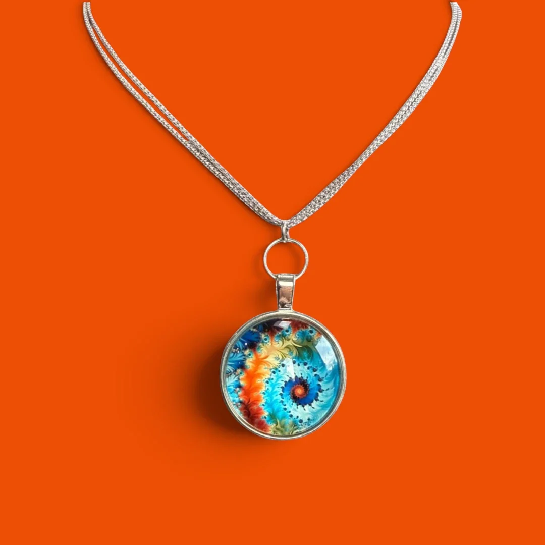 Silver chain pendant necklace with blue and orange swirl patterned pendant made by Color Cult and placed against an orange background.