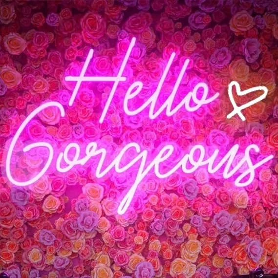 Neon sign that reads 'Hello Gorgeous' with a heart, against a background of pink, purple, and peach-colored roses.