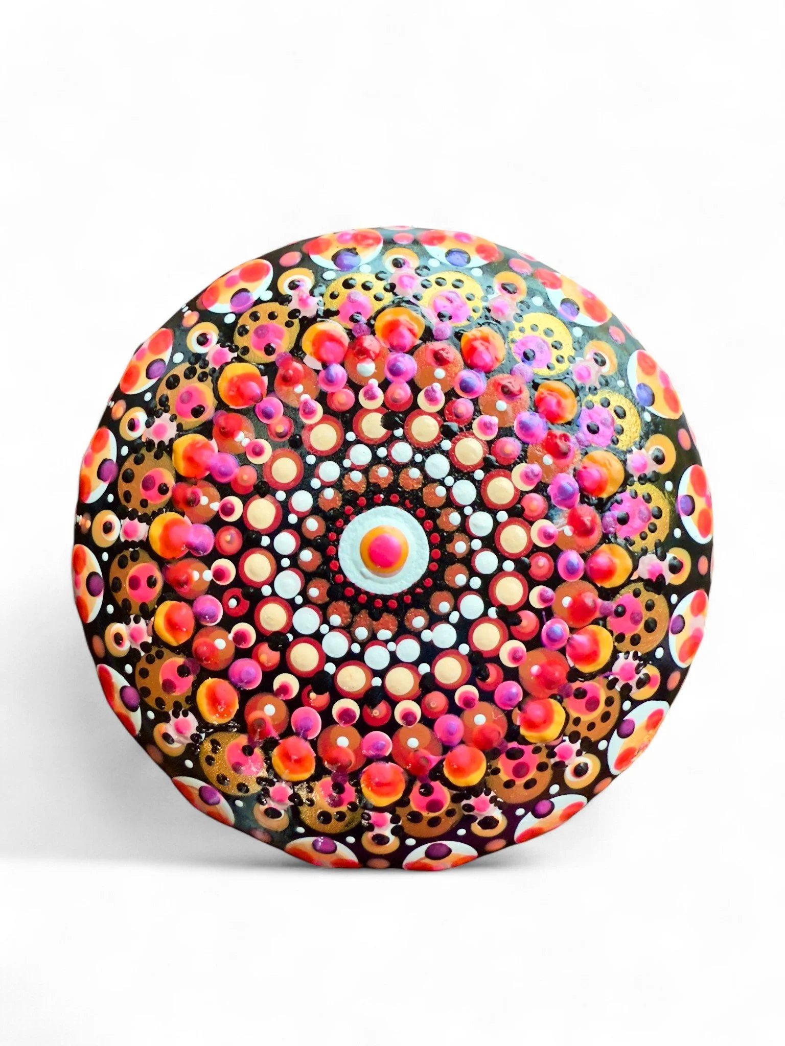 Colorful, circular, dot-painted rock displaying intricate mandala pattern with pink, orange, purple, white, and black dots against a white background.