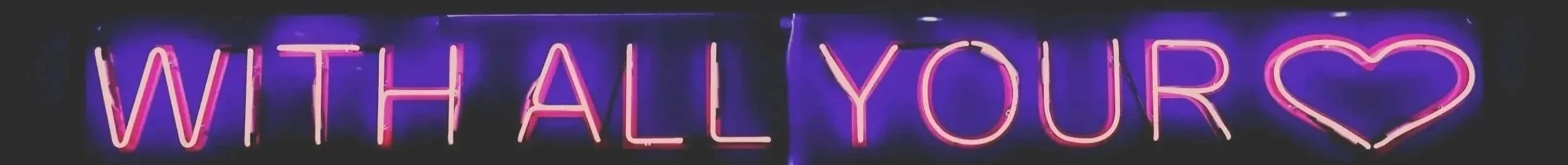 Neon sign that reads 'WITH ALL YOUR' with a heart shape at the end.