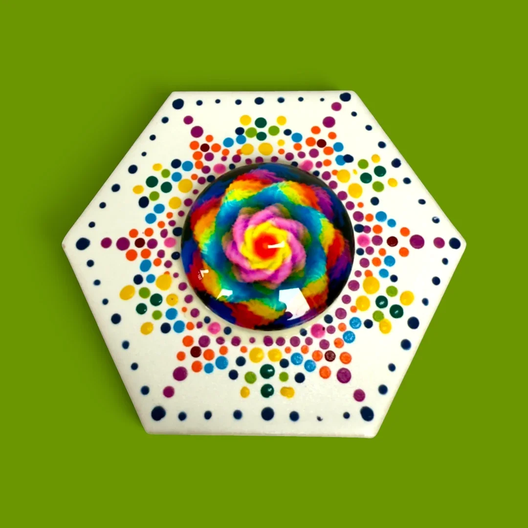 A hexagonal magnet that has been hand-painted with intricate dot mandala designs.