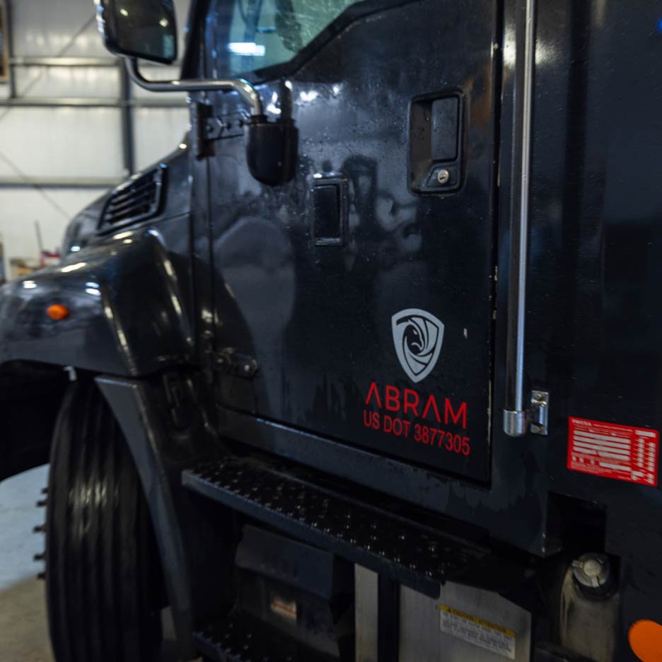 Side view of black truck with "ABRAM" logo and US DOT number in a garage