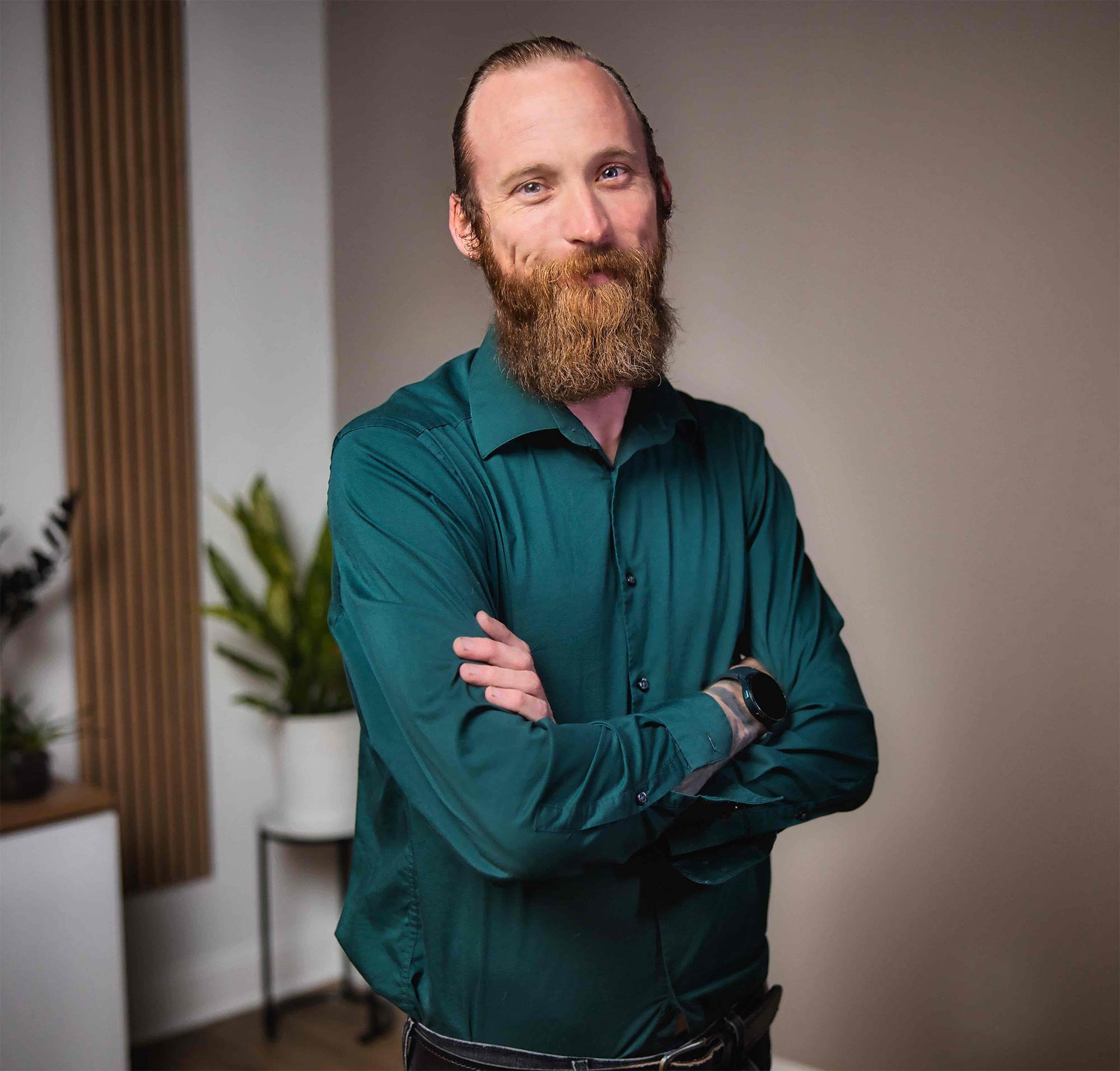 Man with a beard in a green shirt crossing arms