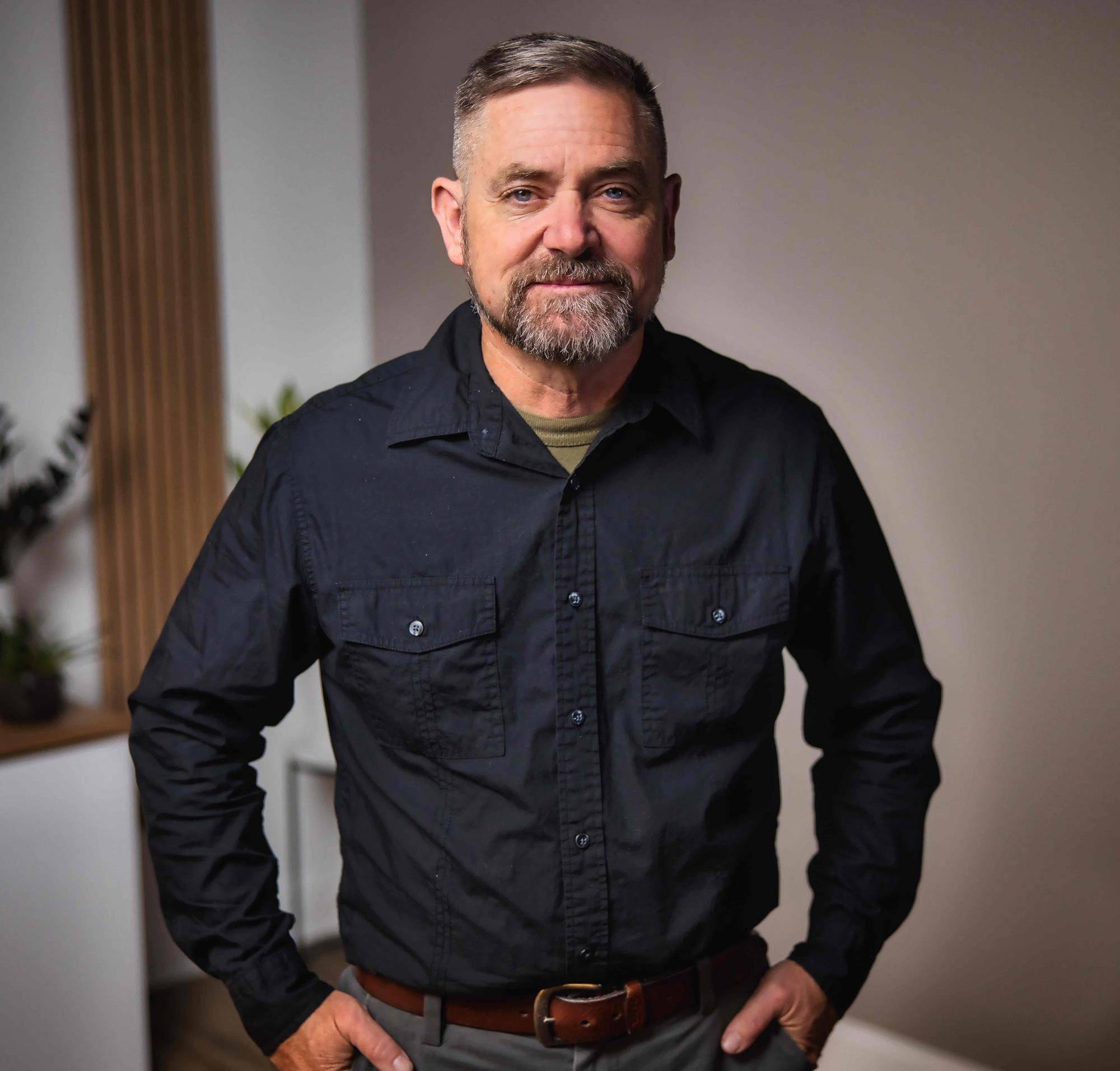 Man with beard in black shirt standing indoors