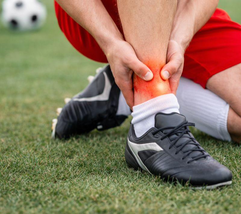 Soccer player with acute ankle sprain and swelling during sports activity needing sports medicine treatment.