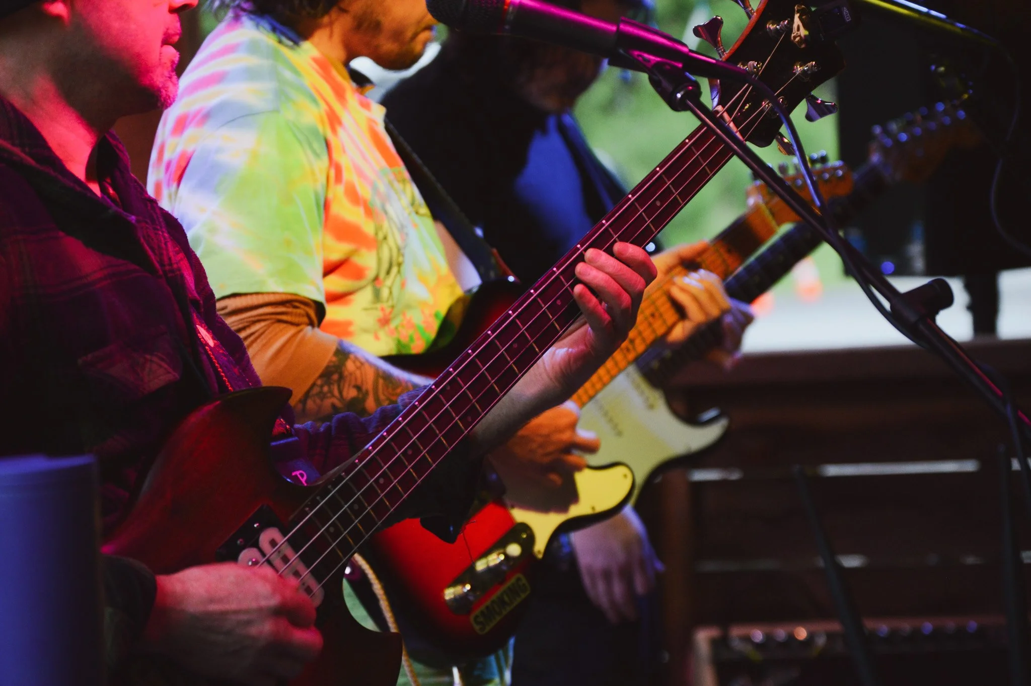 A group of musicians playing electric guitars and singing into microphones during a live performance.