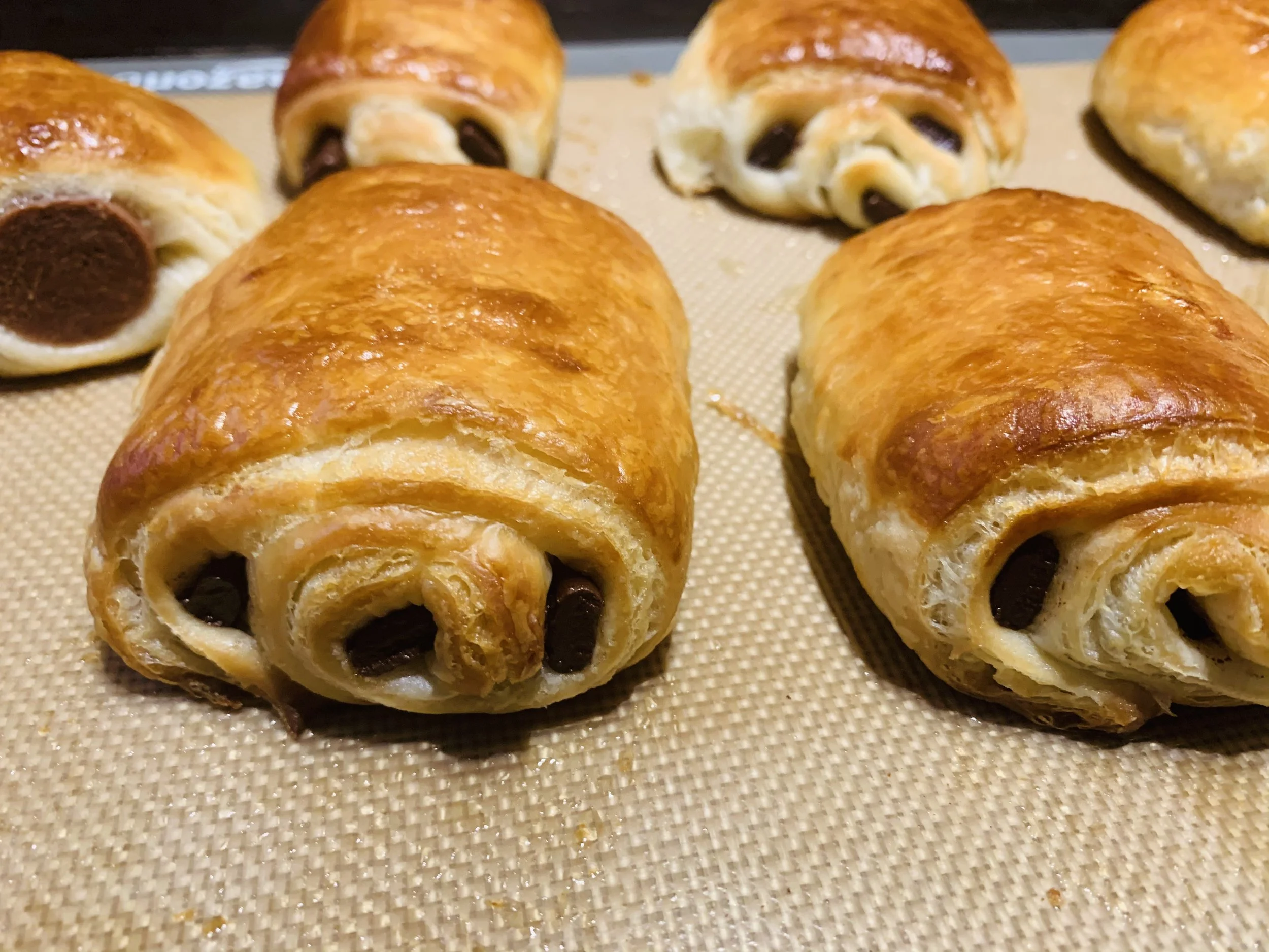 Baked croissants with chocolate chips on a baking sheet.