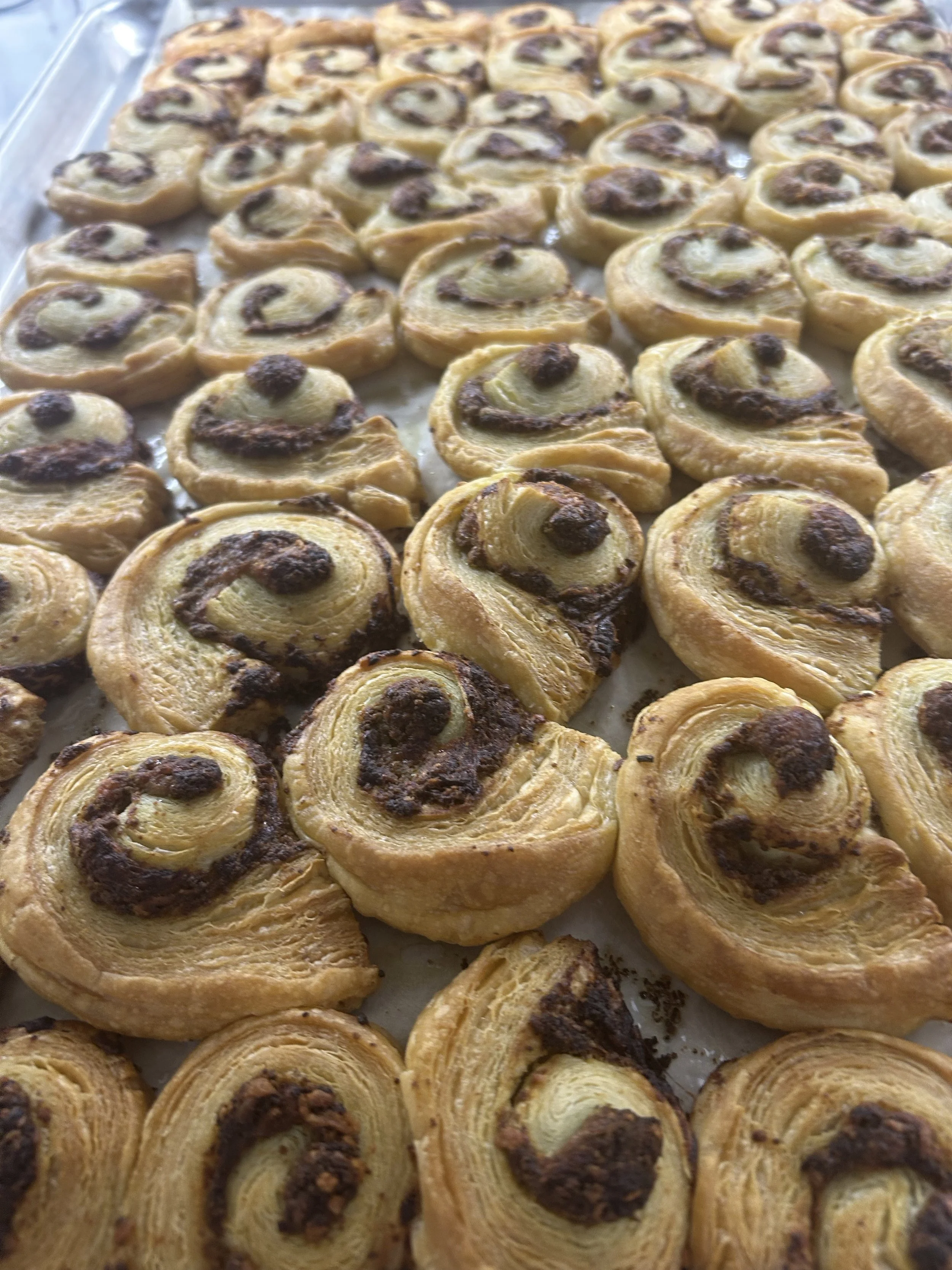 Multiple Danish pastry pinwheels filled with cream and chocolate on a baking tray.