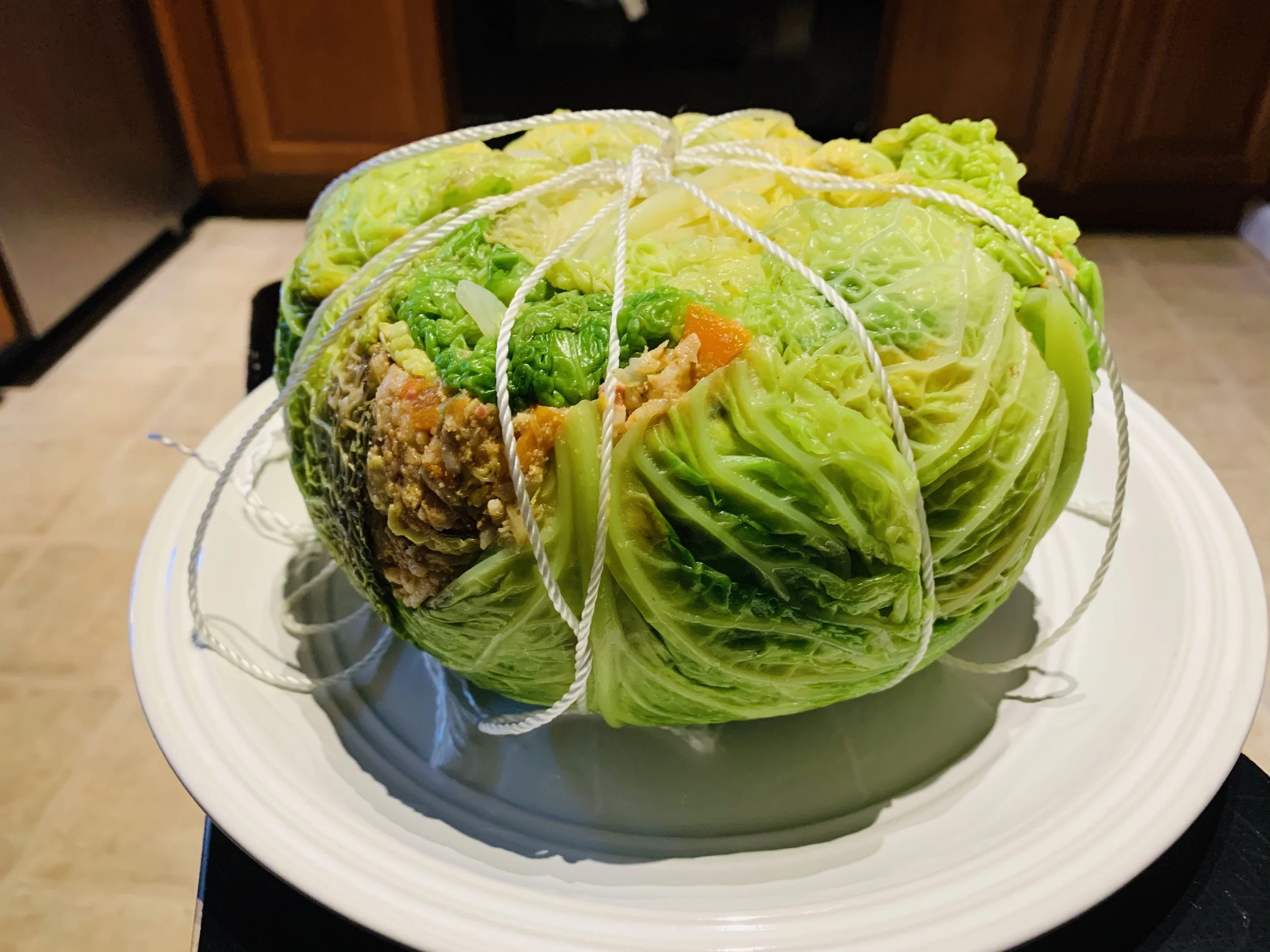 A ball of lettuce wrapped with string on a white plate