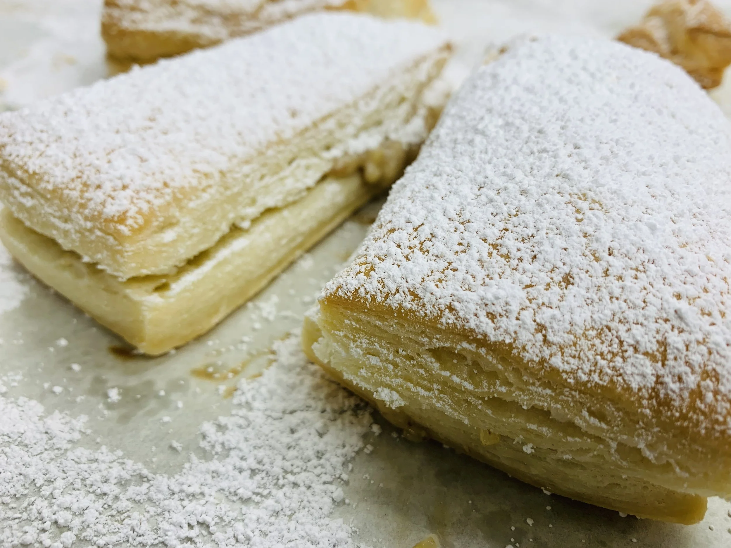Close-up of sliced cheesecake topped with powdered sugar on a flat surface.