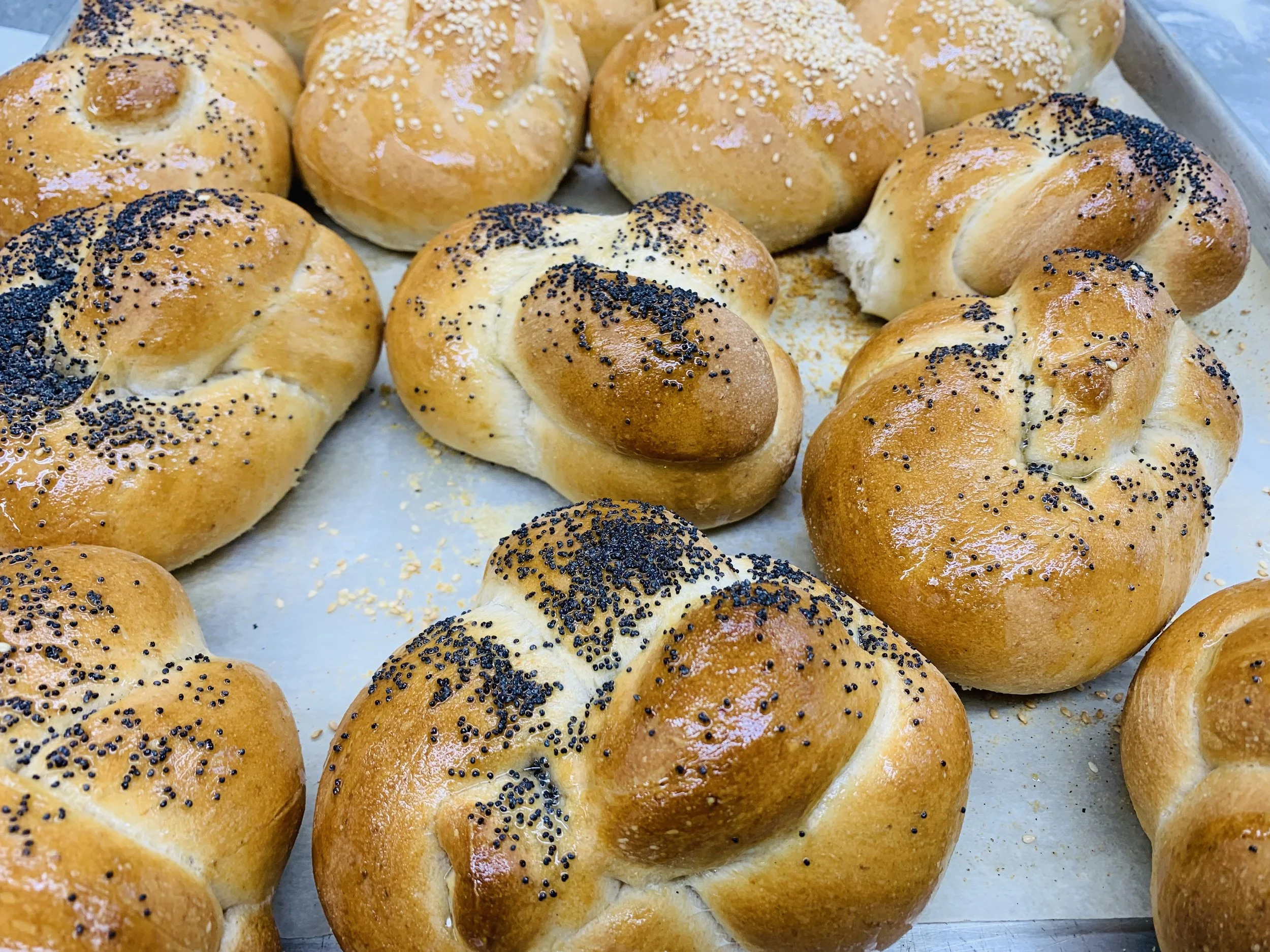 Close-up of freshly baked bread rolls sprinkled with poppy seeds and sesame seeds on top.