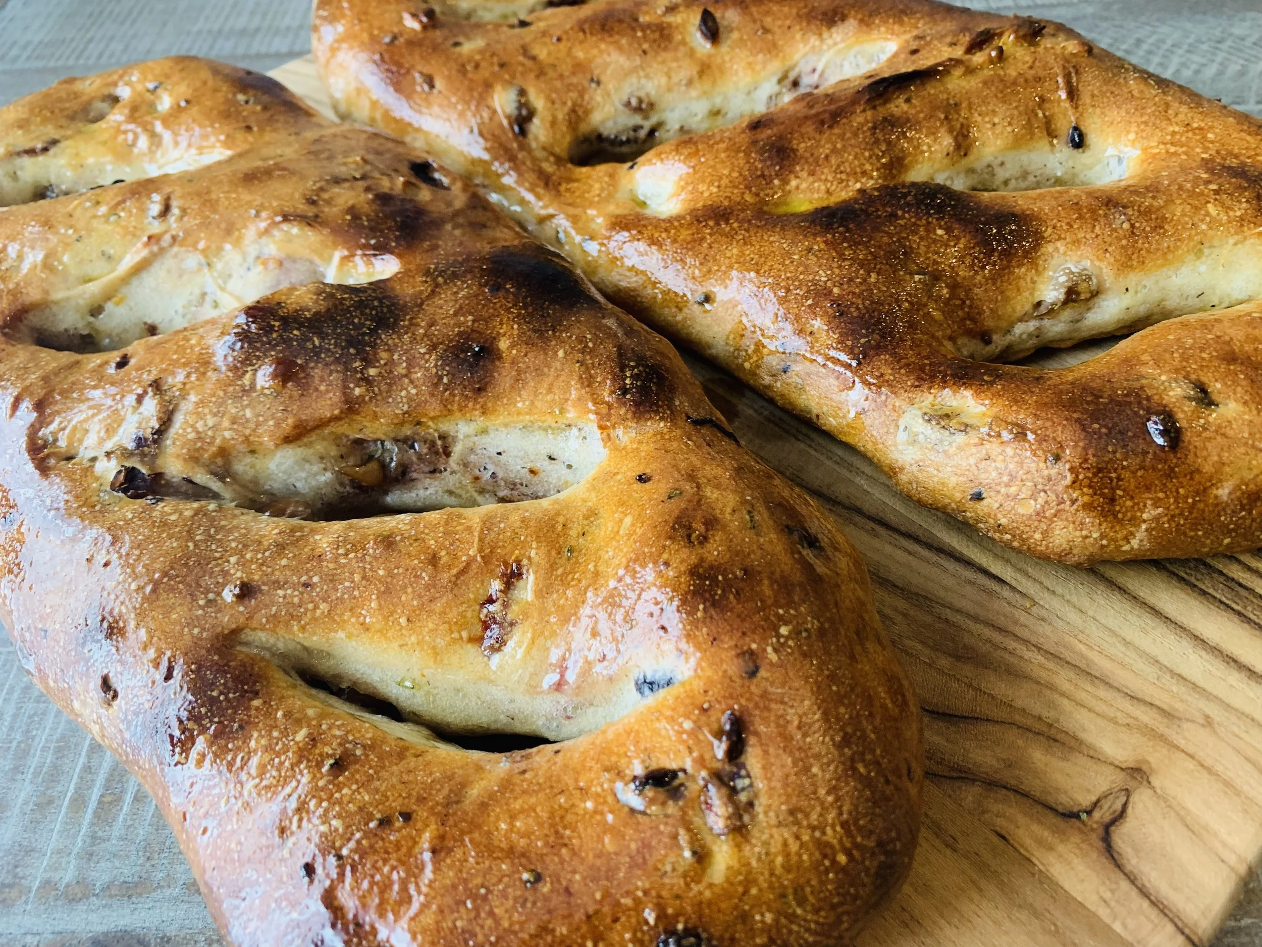 Close-up of freshly baked raisin bread with a golden-brown crust on a wooden cutting board.
