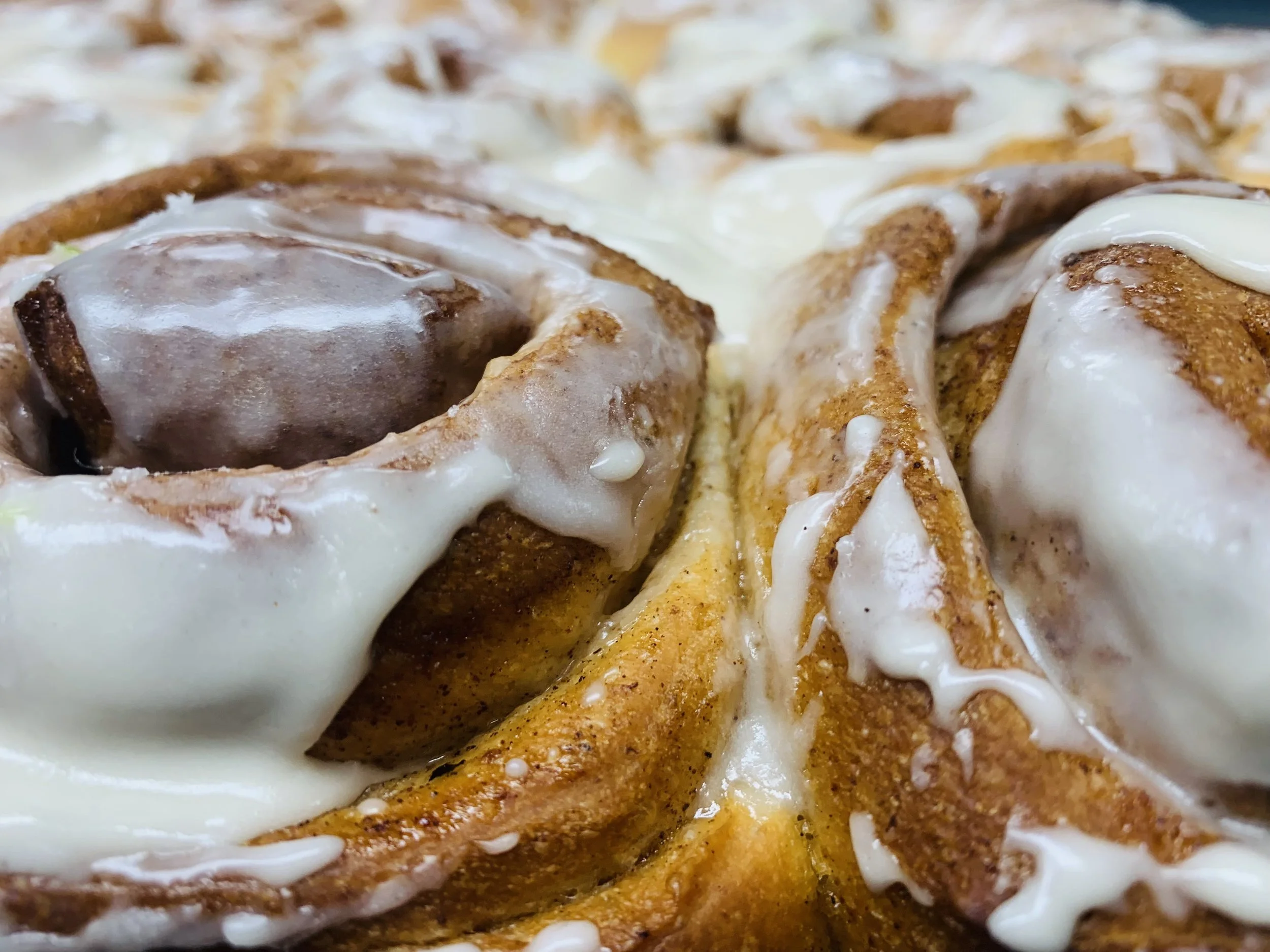 Close-up of cinnamon rolls with white icing drizzled on top.