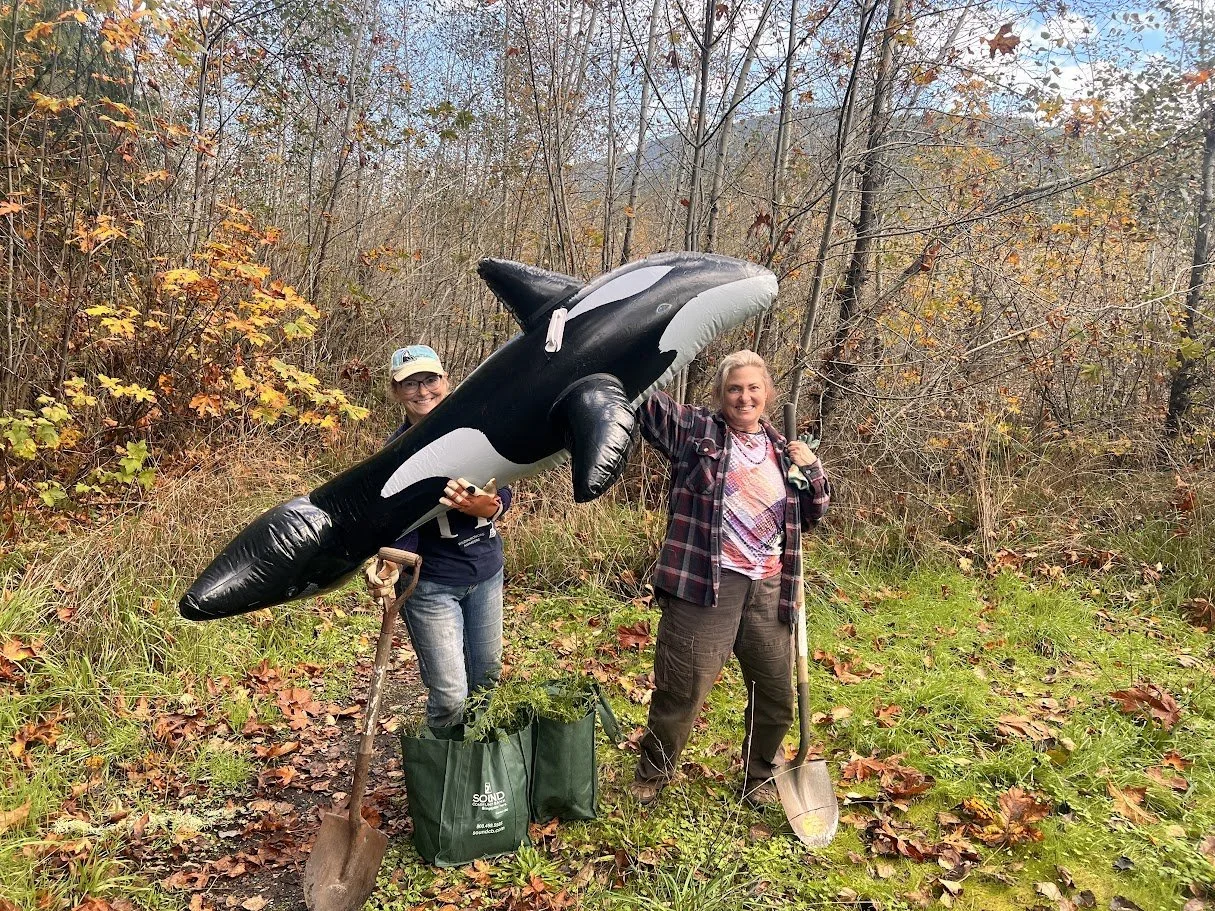 Image of two volunteers smiling while holding the blow up orca