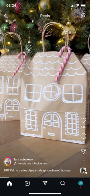 Decoratieve cadeaudozen gemaakt van kralen met huisvormen en versieringen, geplaatst onder een versierde kerstboom.